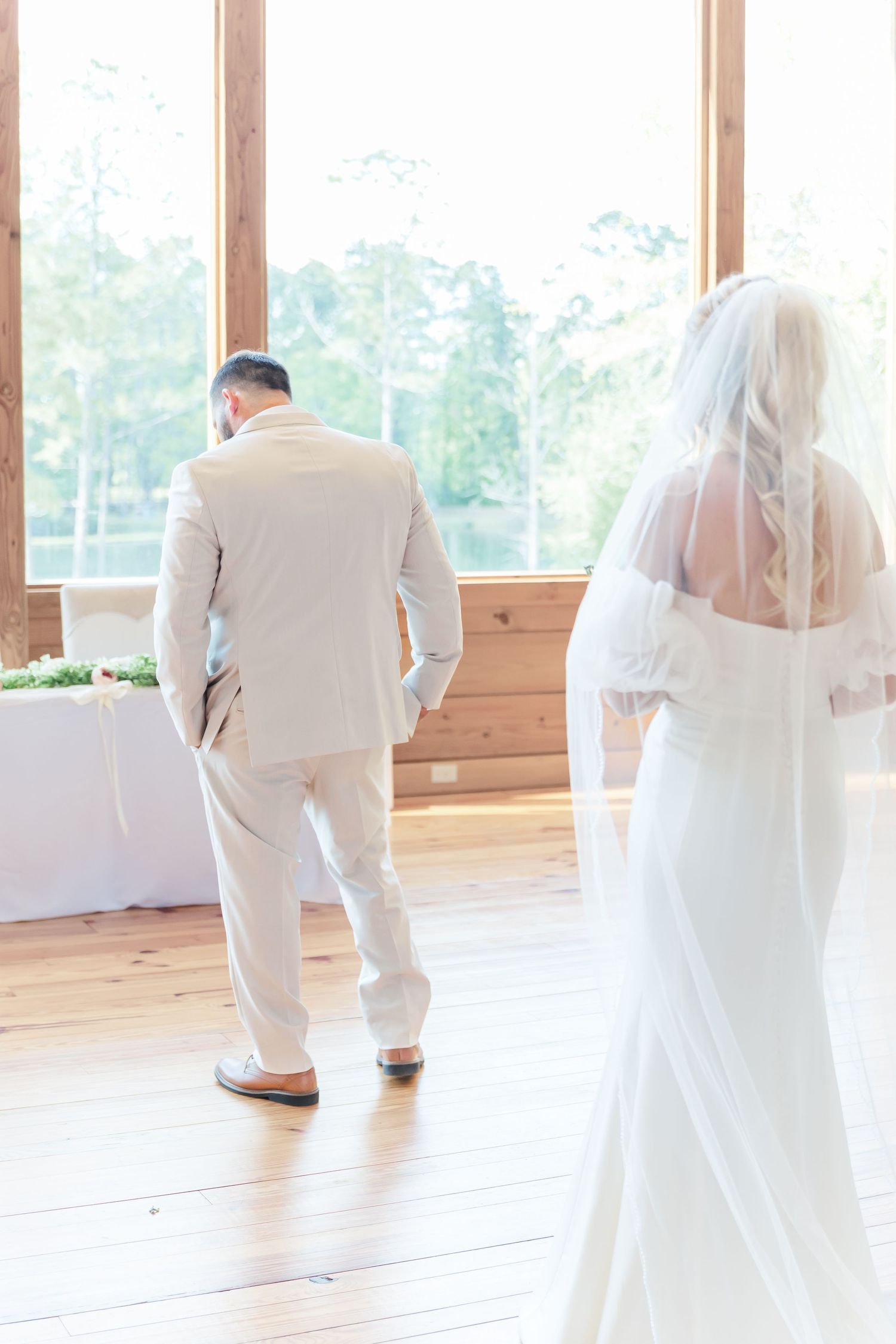 A couple shares a private first look moment in a sunlit room with wooden walls and floors.