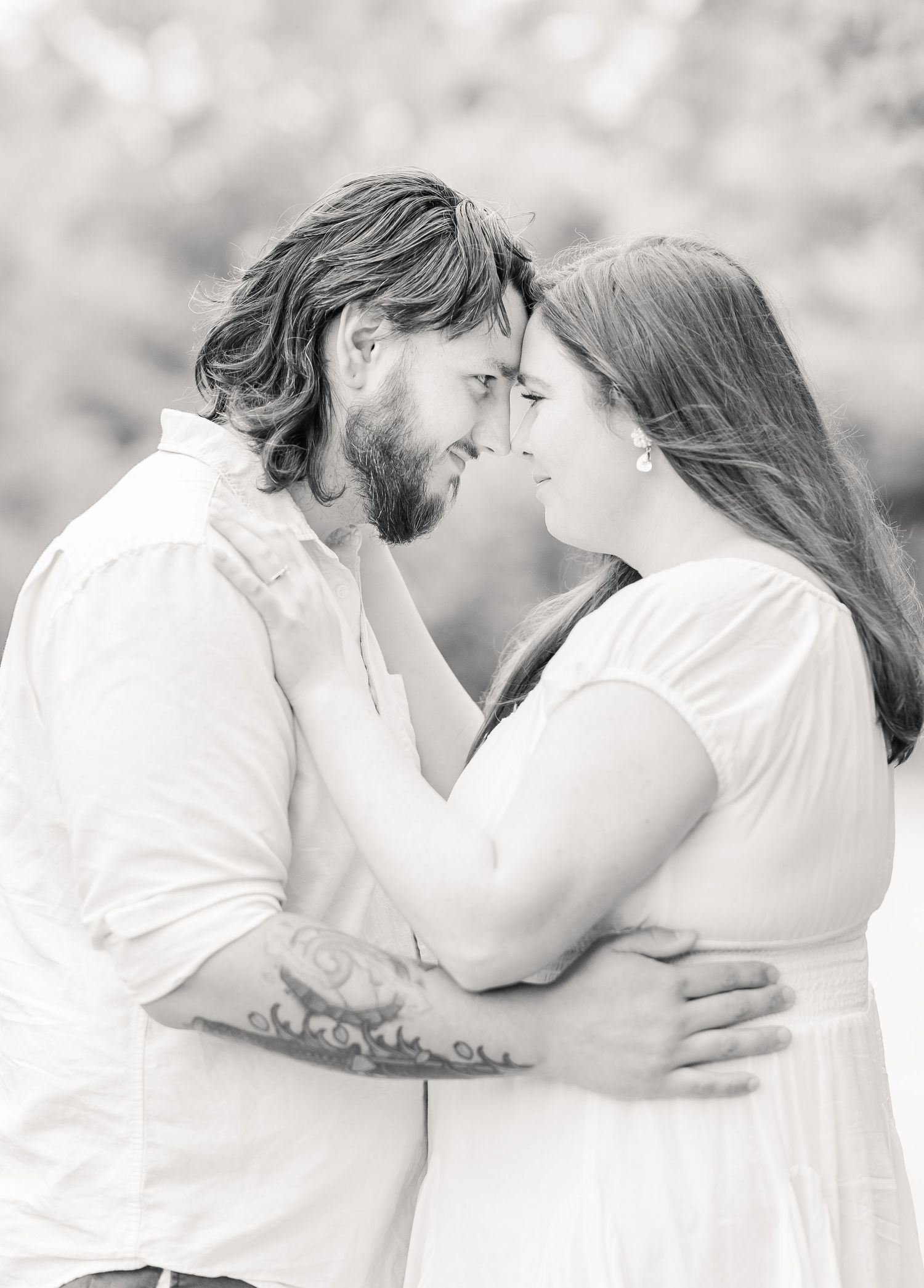 Black and white portrait of a couple in a tender embrace outdoors.