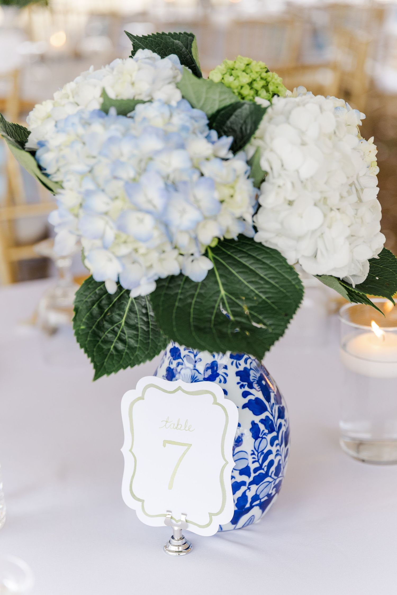 Blue and white chinoiserie vase with white and blue hydrangea centerpiece and table number 7 sign.