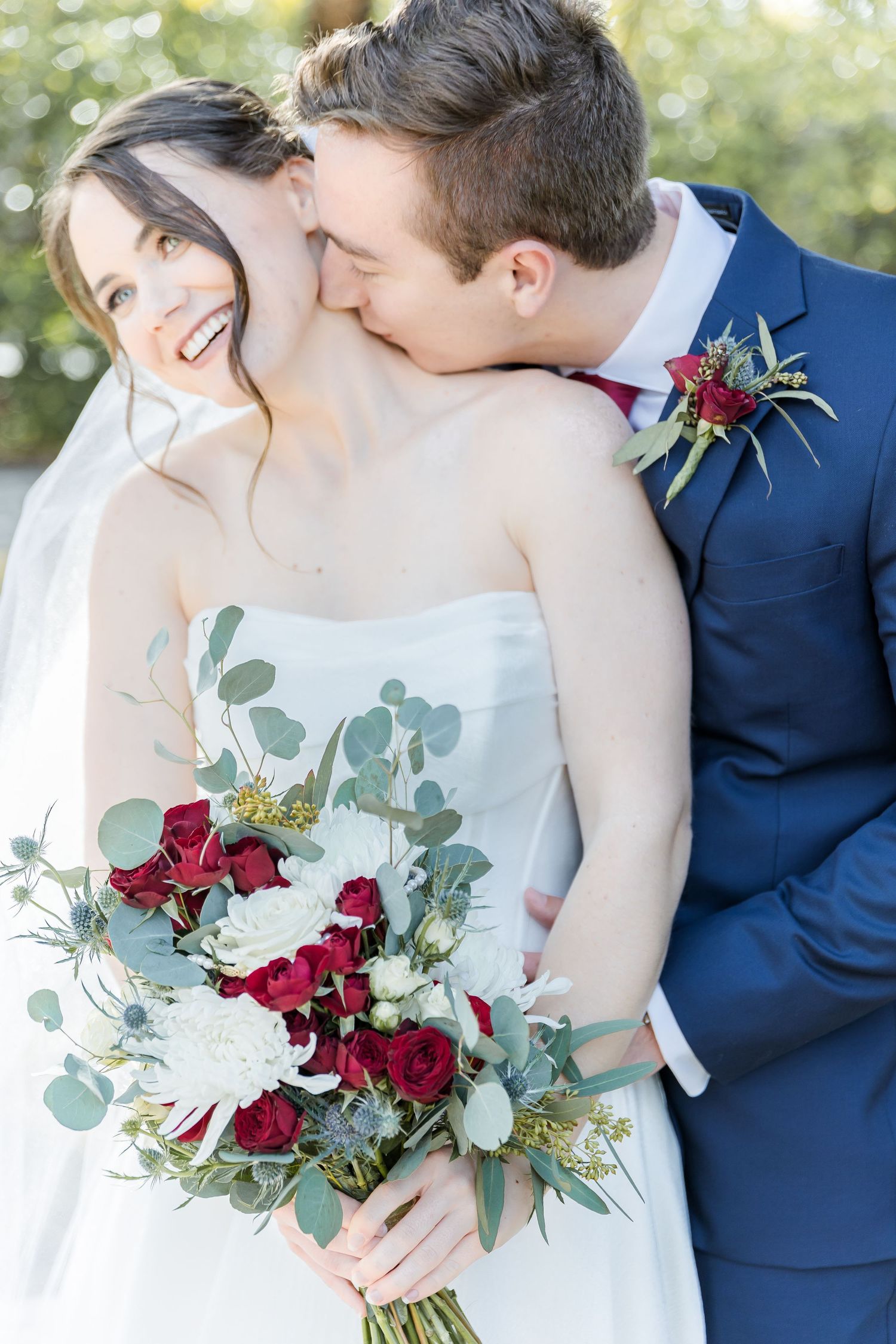 A romantic moment with red and white bouquet featuring eucalyptus leaves.