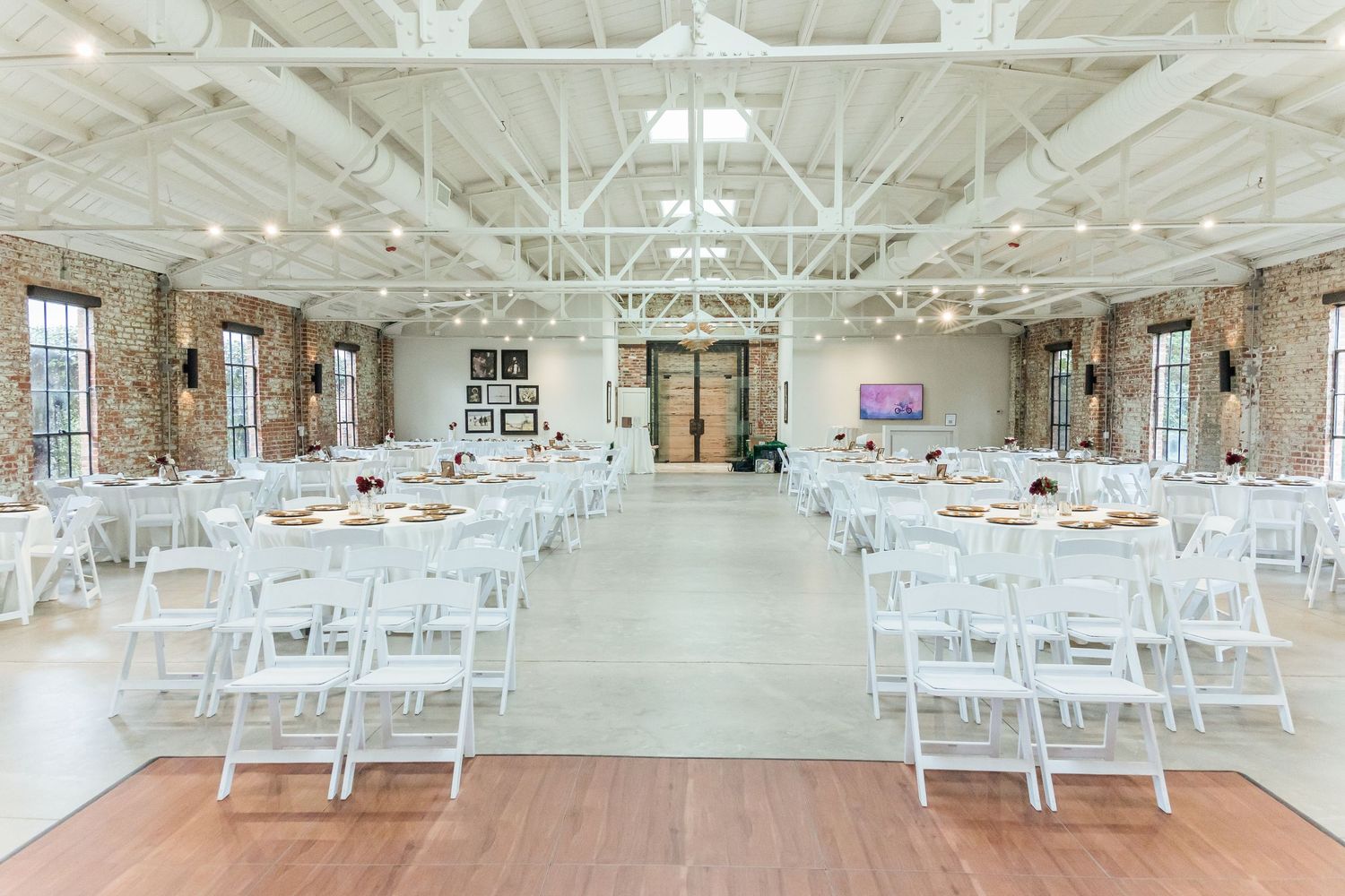 Modern industrial wedding venue with exposed brick walls and white chairs set up for ceremony reception.
