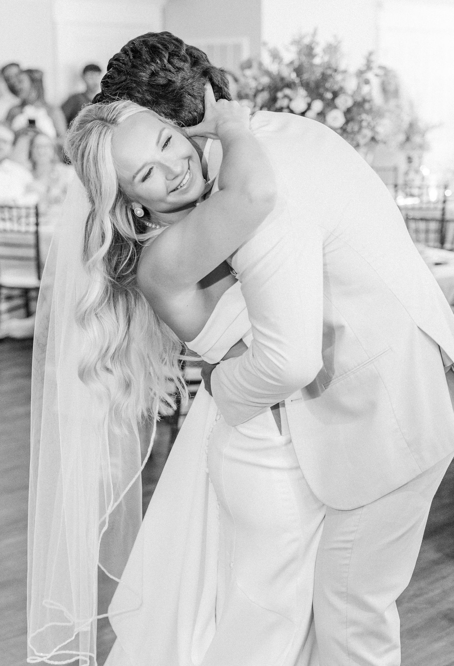 Black and white photo of bride and groom sharing an emotional first dance embrace at reception.