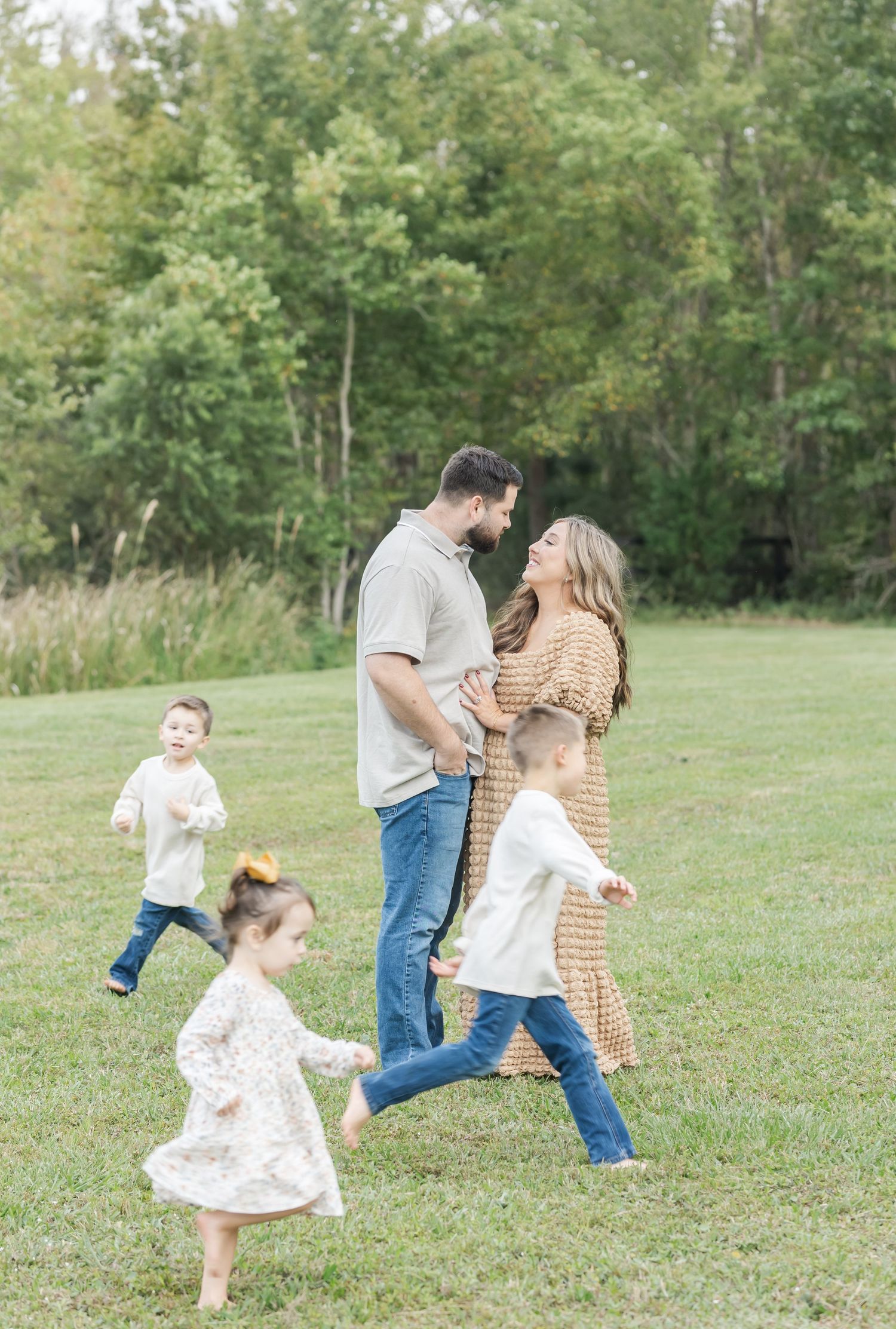 Family plays and runs together on a grassy field during an outdoor photo session.