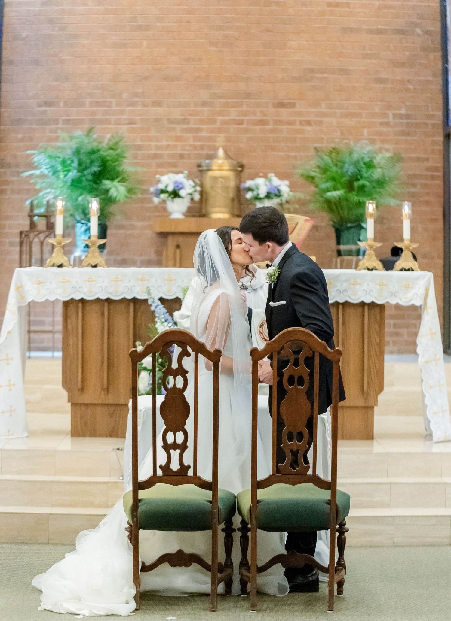 Decorated church altar with wooden chairs and greenery arrangements for a wedding ceremony.