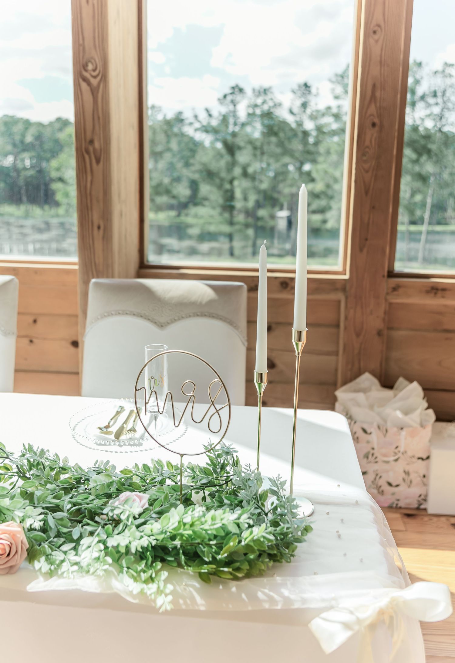 Elegant head table decorated with eucalyptus garland, rose gold accents, and circular wedding signage.