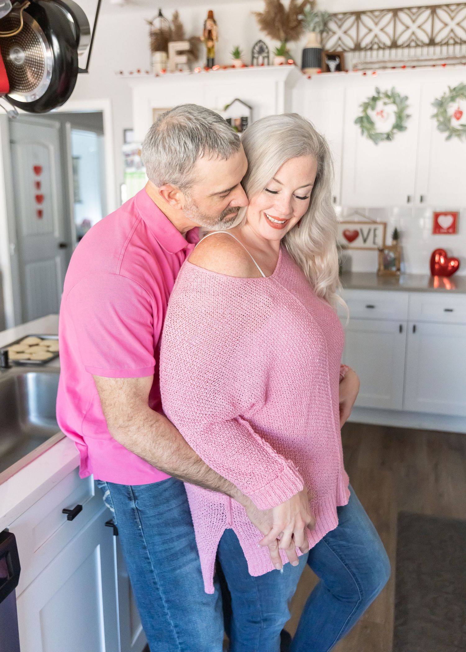 A tender kitchen photoshoot with a couple in coordinating pink outfits.