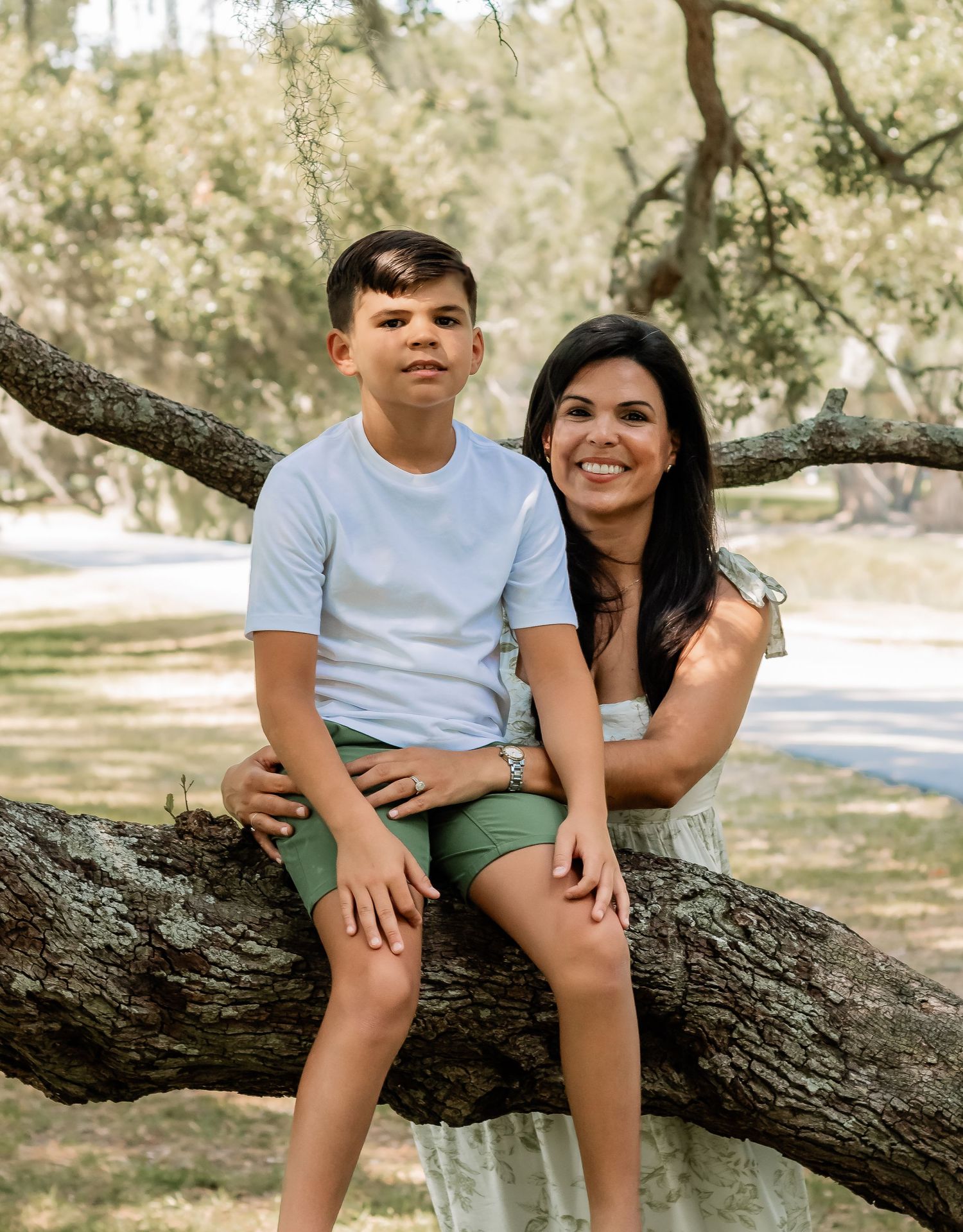 A sweet candid moment captured on a fallen tree branch in a park setting.