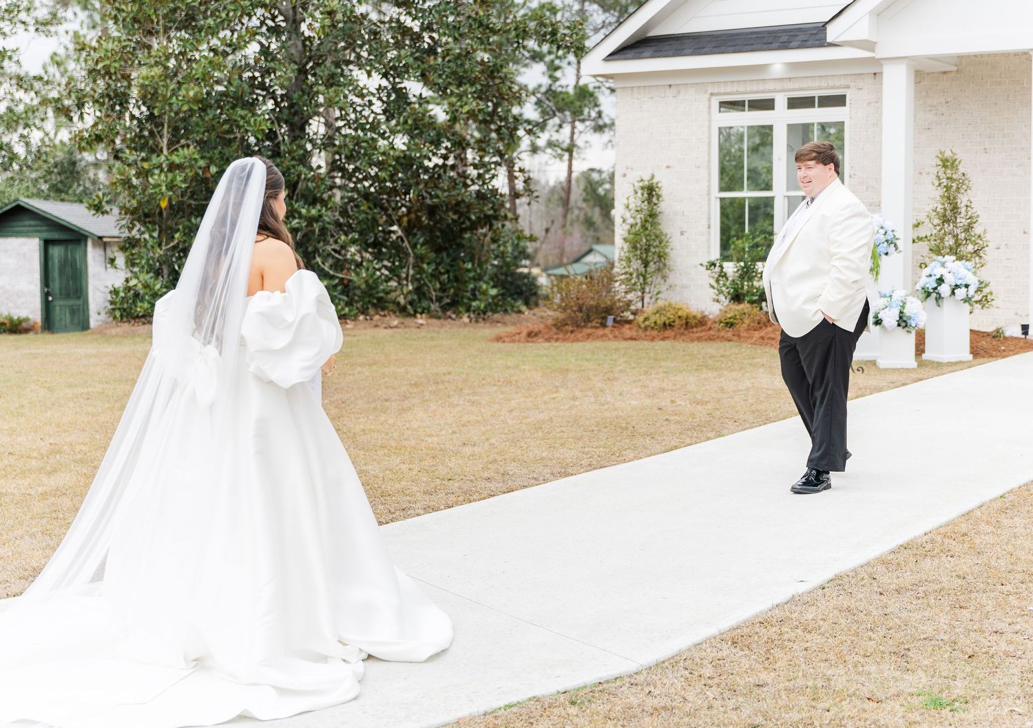 Bride in a white off-shoulder gown with veil during first look with groom outdoors.