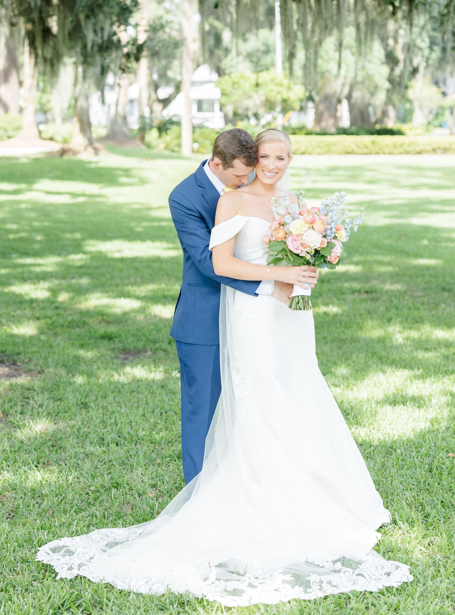A romantic wedding photo series showing a bride in a flowing white dress being spun around in a sunlit garden setting.