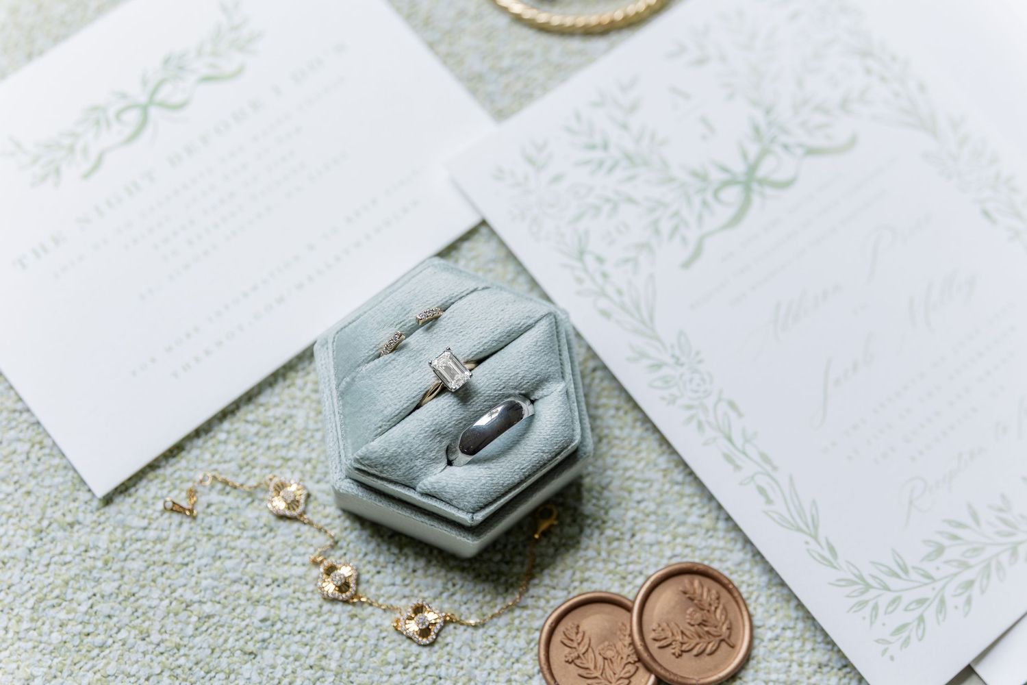 A small gray hexagonal ring box with gold rings and pennies on delicate white lace.