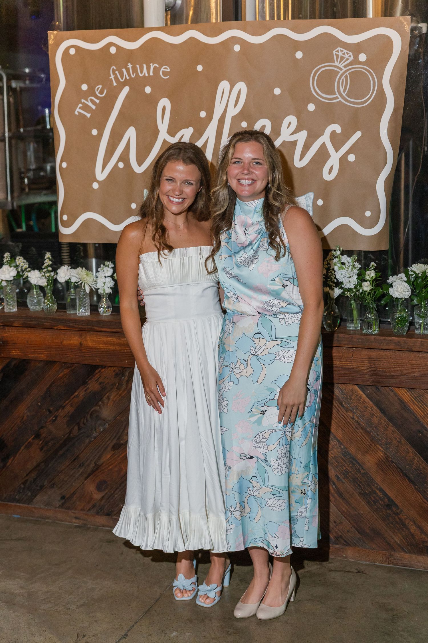 Two women smiling together at a bridal shower in front of a future Walkers banner.