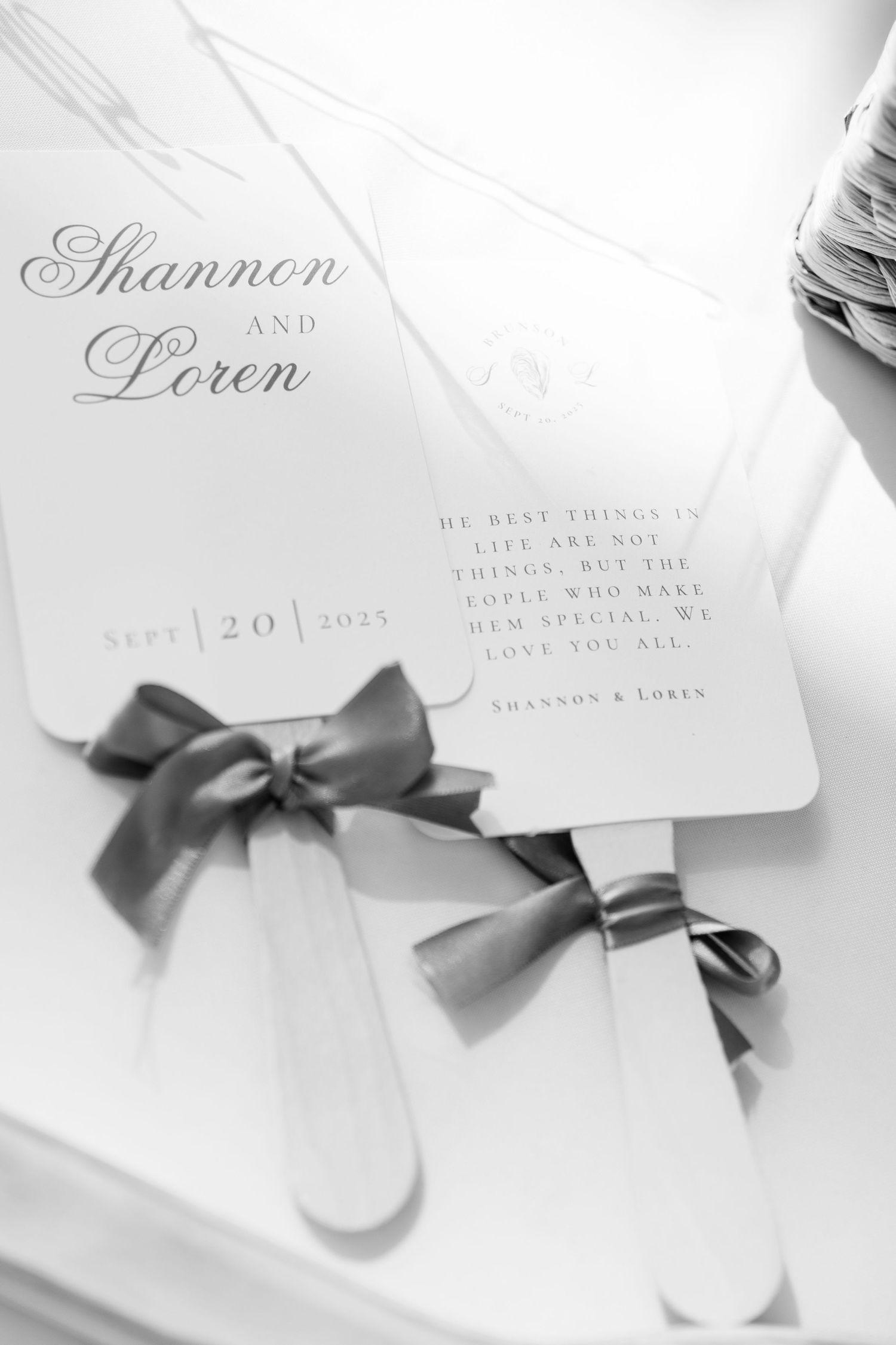 Elegant wedding invitations with gray ribbons and calligraphy text on white paper.