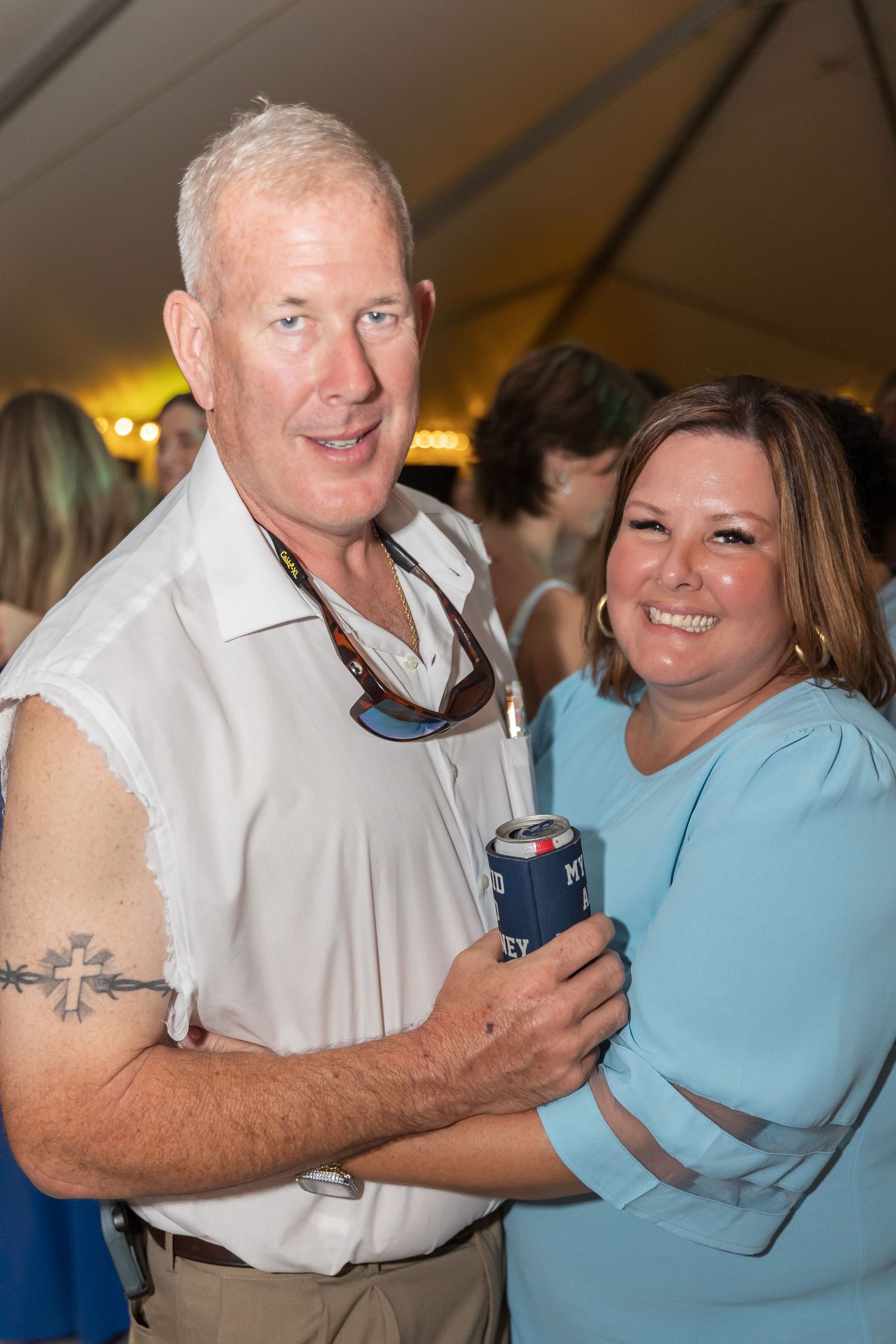 Party guests in casual attire smile while holding beverages at an indoor event.
