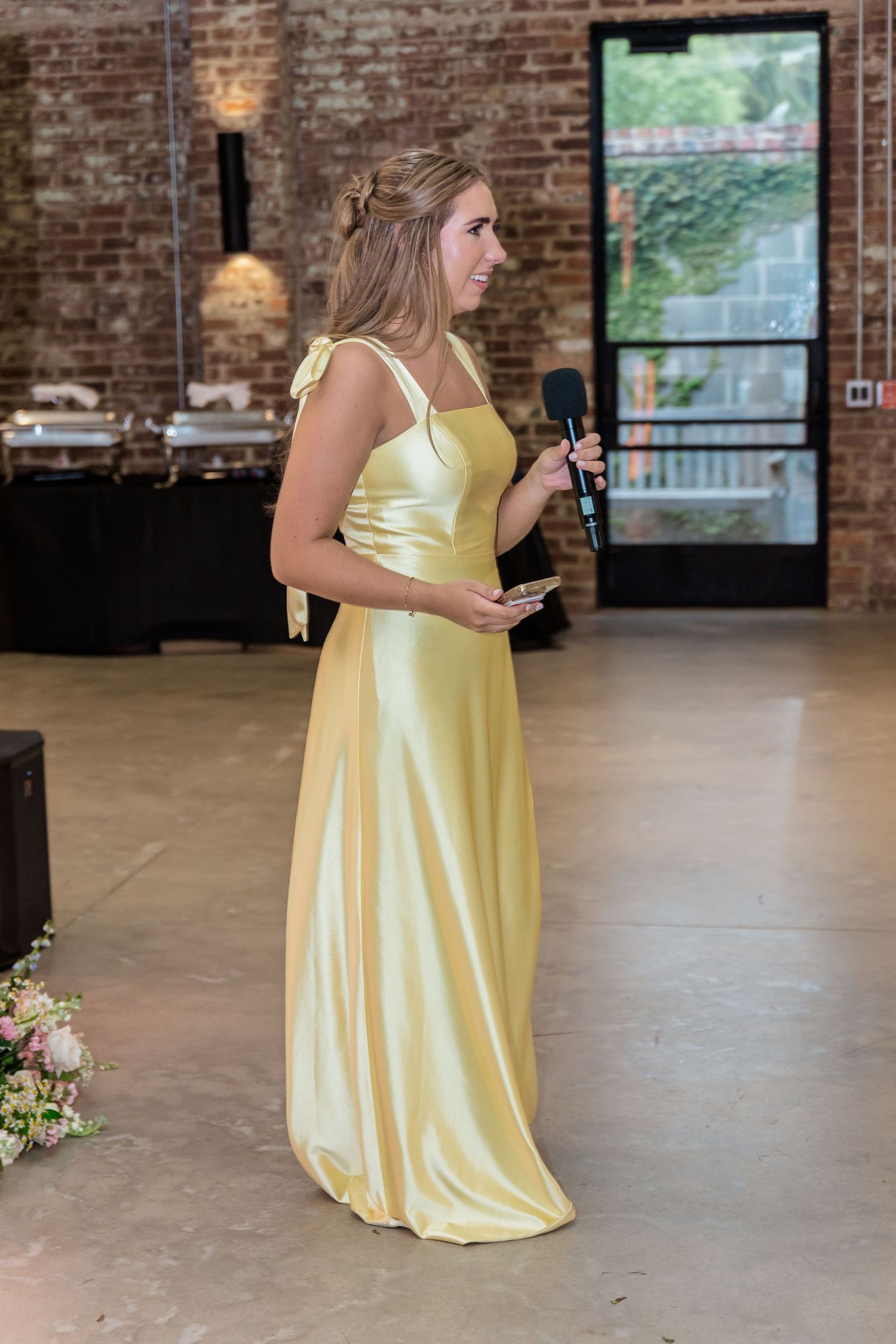 Yellow bridesmaid dresses against exposed brick walls at an indoor wedding venue.