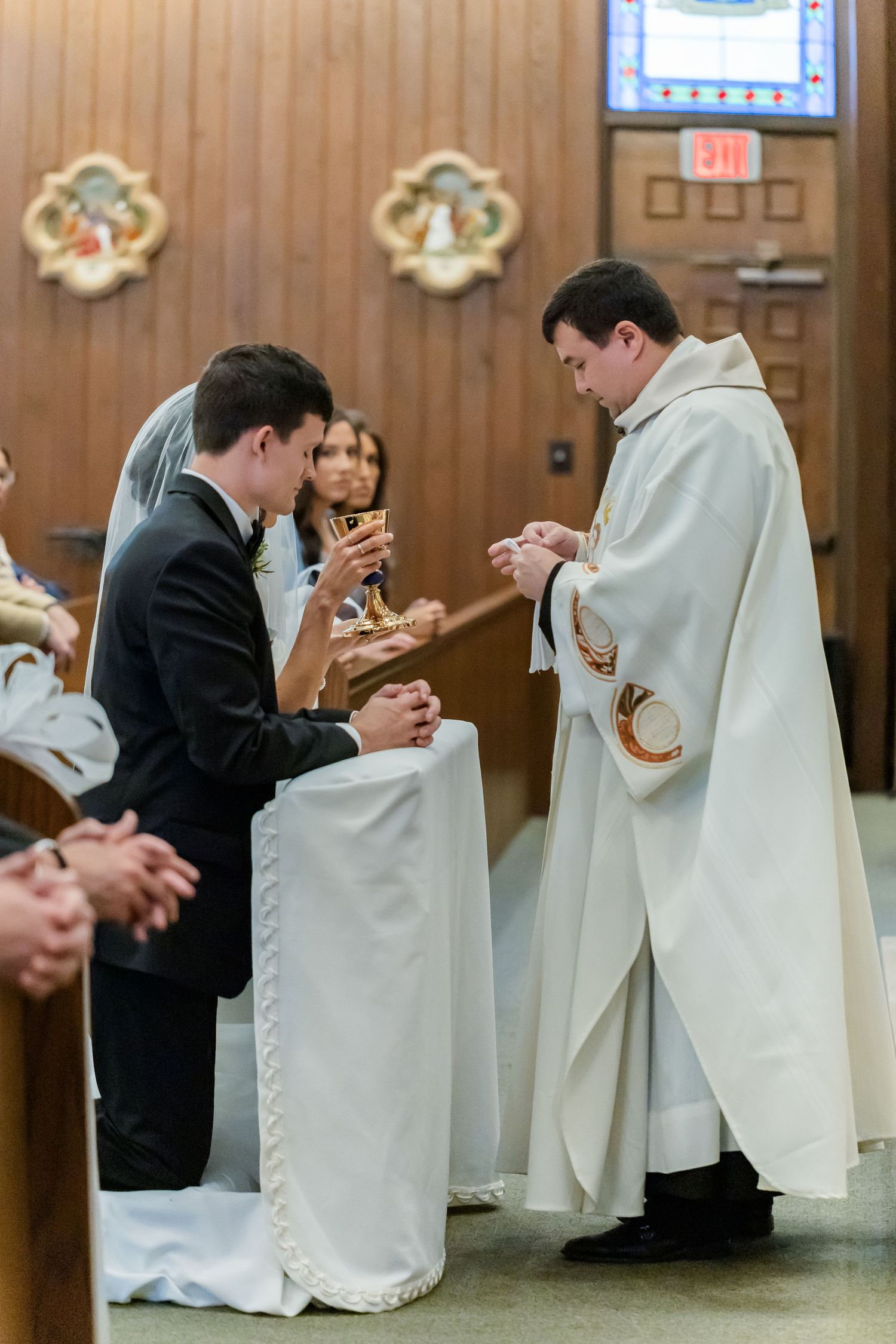Priests in white robes conducting a religious wedding ceremony in a church.