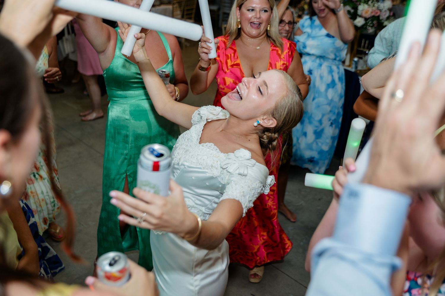 Guests enjoying themselves and dancing at a wedding reception with colorful lighting and decor.