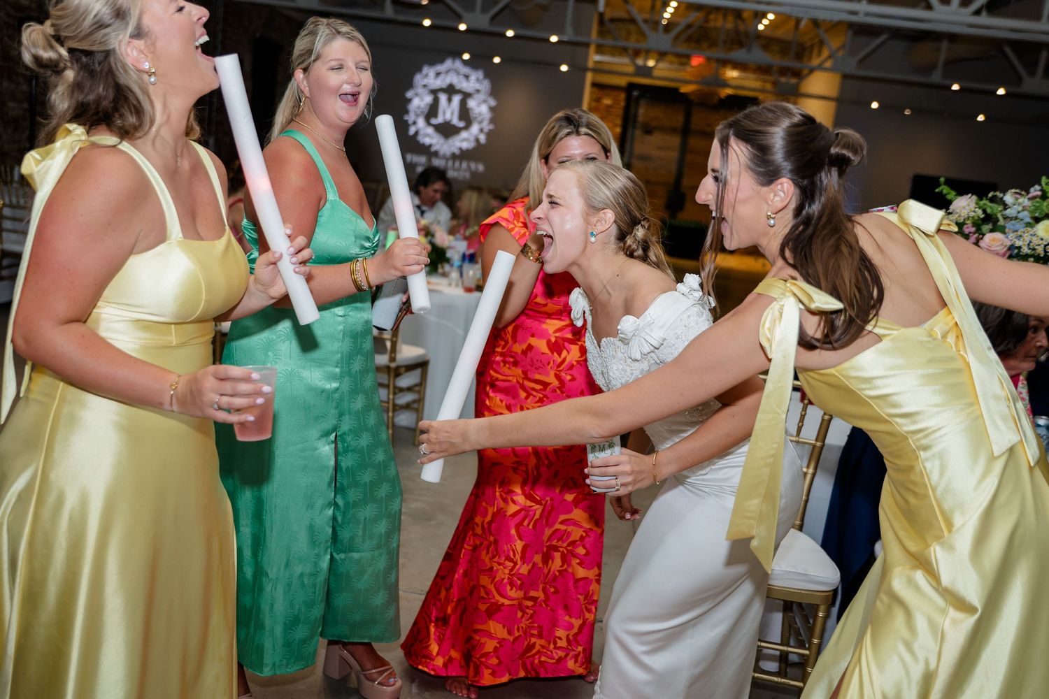 People in colorful formal dresses dancing and celebrating at a festive party event.