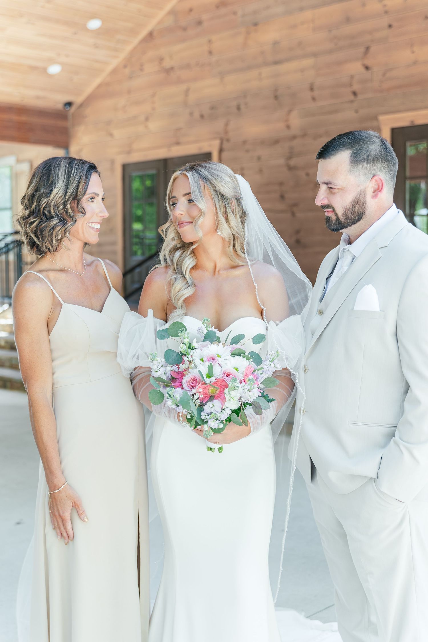 Candid wedding moment captured on rustic venue porch with white and pink florals.