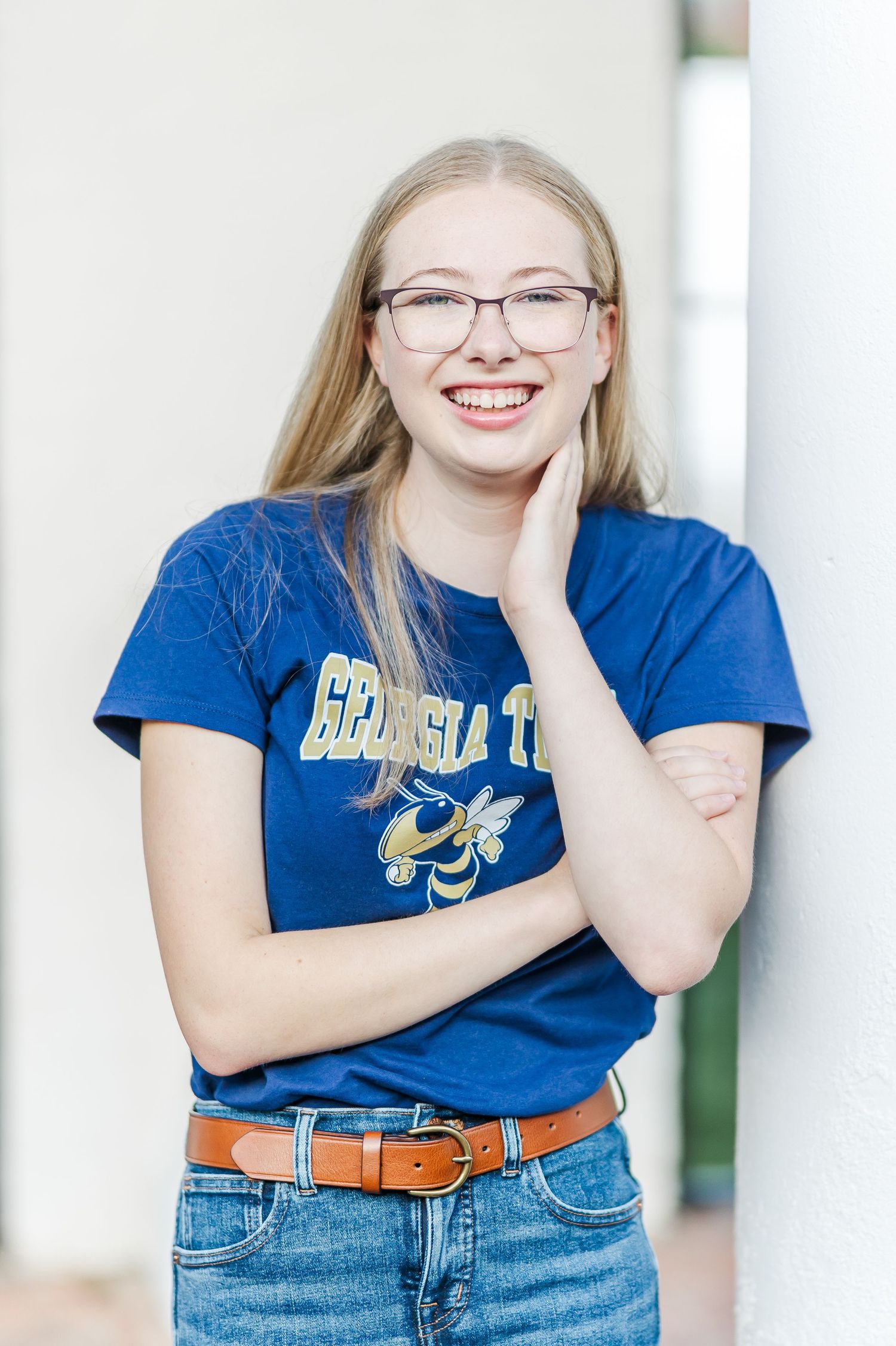 Casual portrait series against white columns showing various expressive poses in blue tee and jeans.