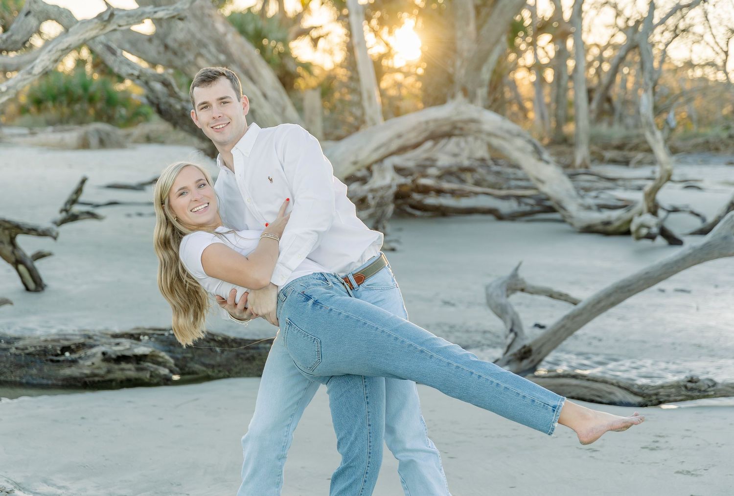 Romantic couple doing a dance dip pose on a beach at sunset.