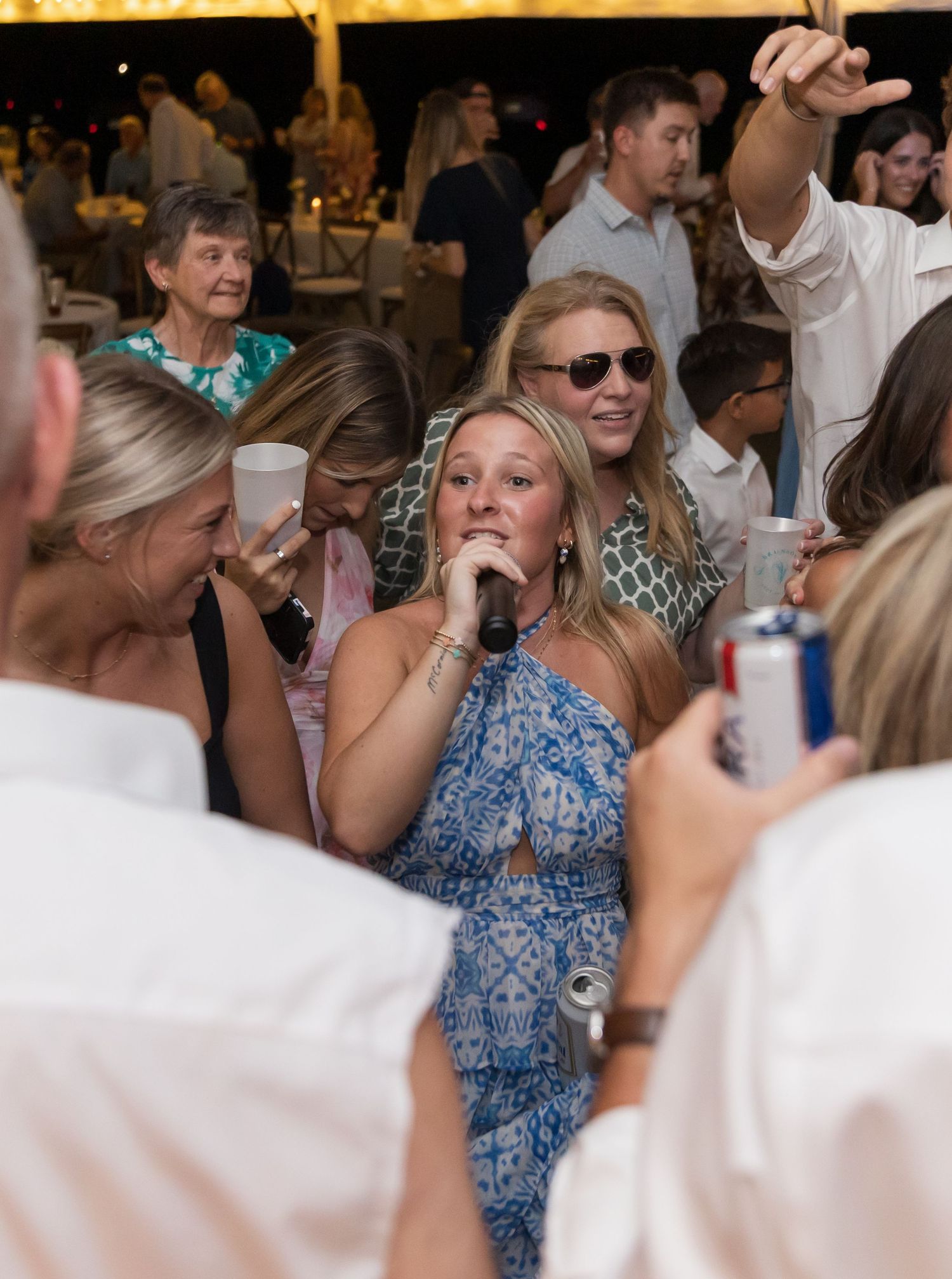 Wedding guests dancing and celebrating on a crowded dance floor at an indoor reception.