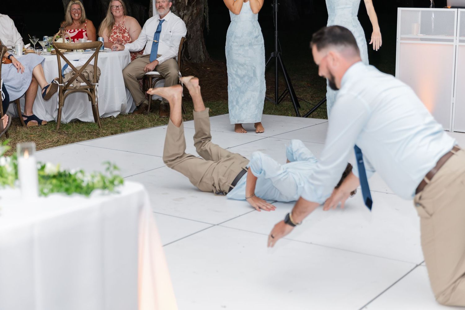 Lively dance party with guests in formal attire enjoying themselves on a white dance floor.