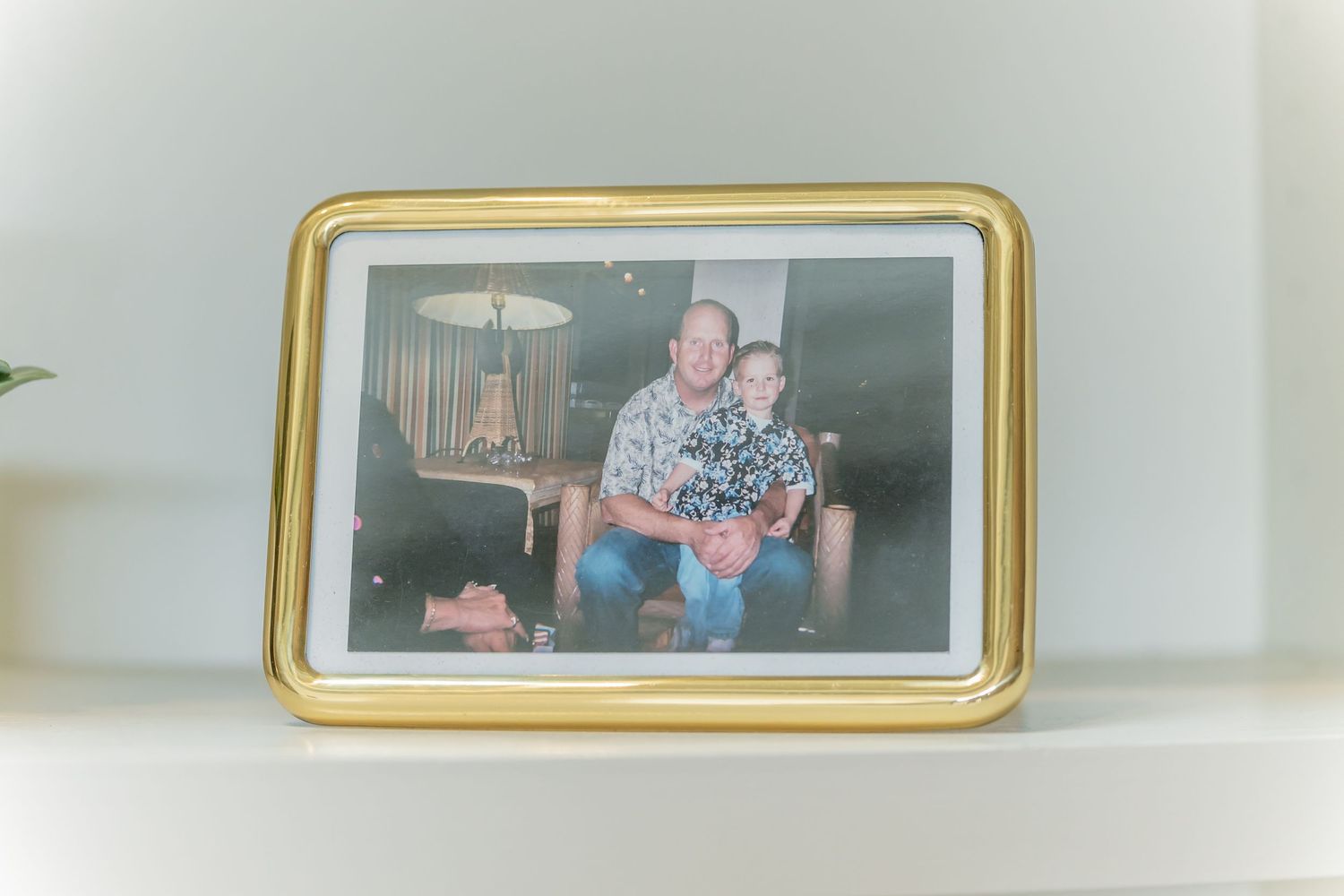 A vintage photograph in a gold frame shows people sitting in a living room with a lamp in the background.