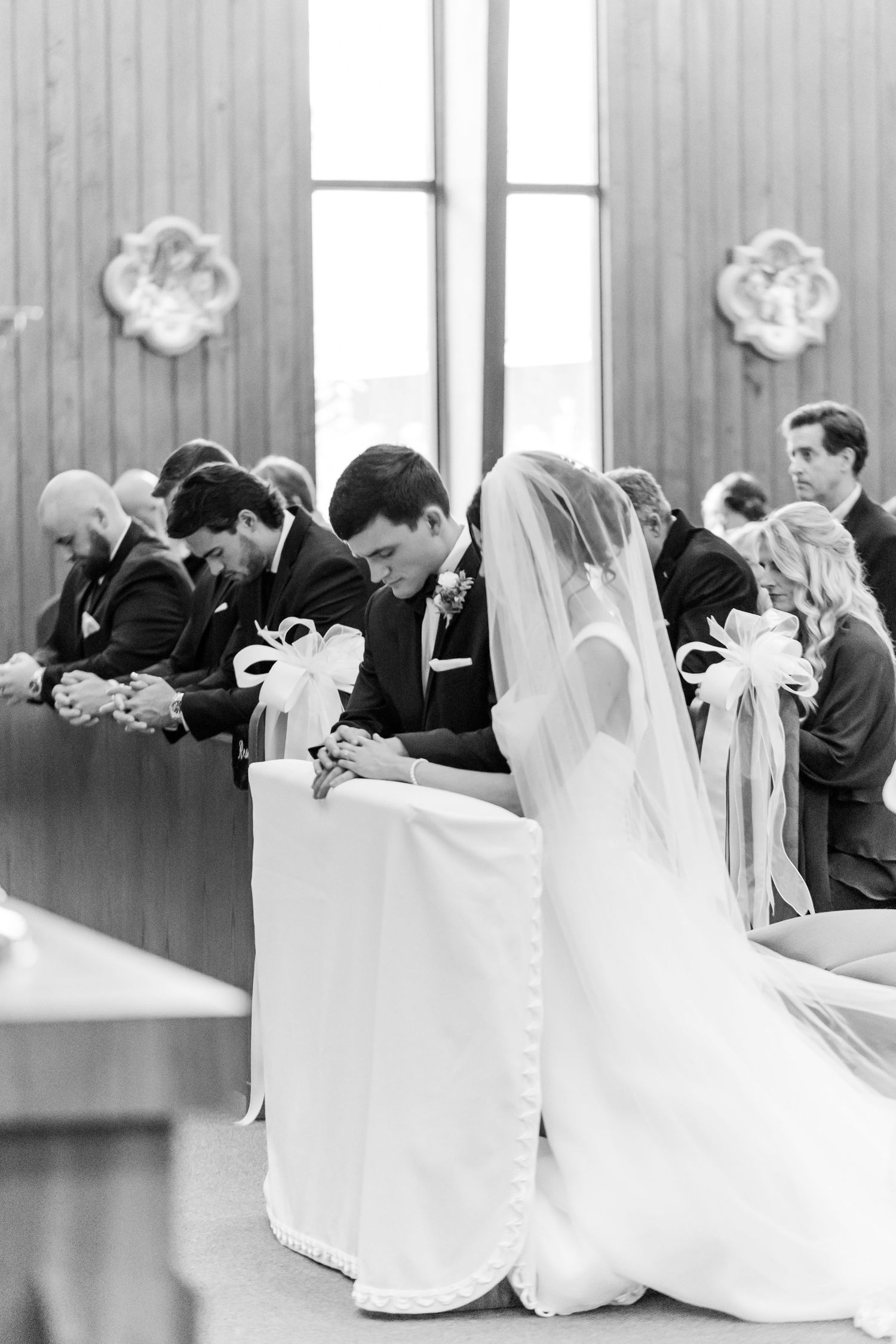Black and white photo of church ceremony with participants in formal attire.