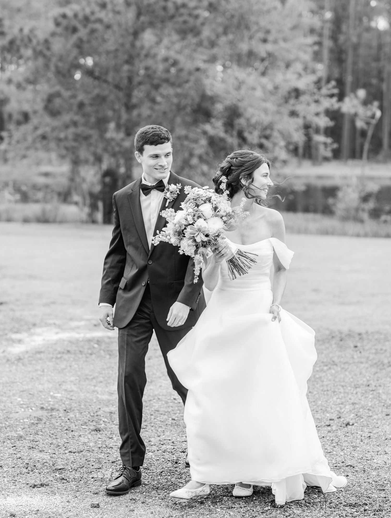 Black and white wedding portraits showing couple dancing and twirling in an open field.