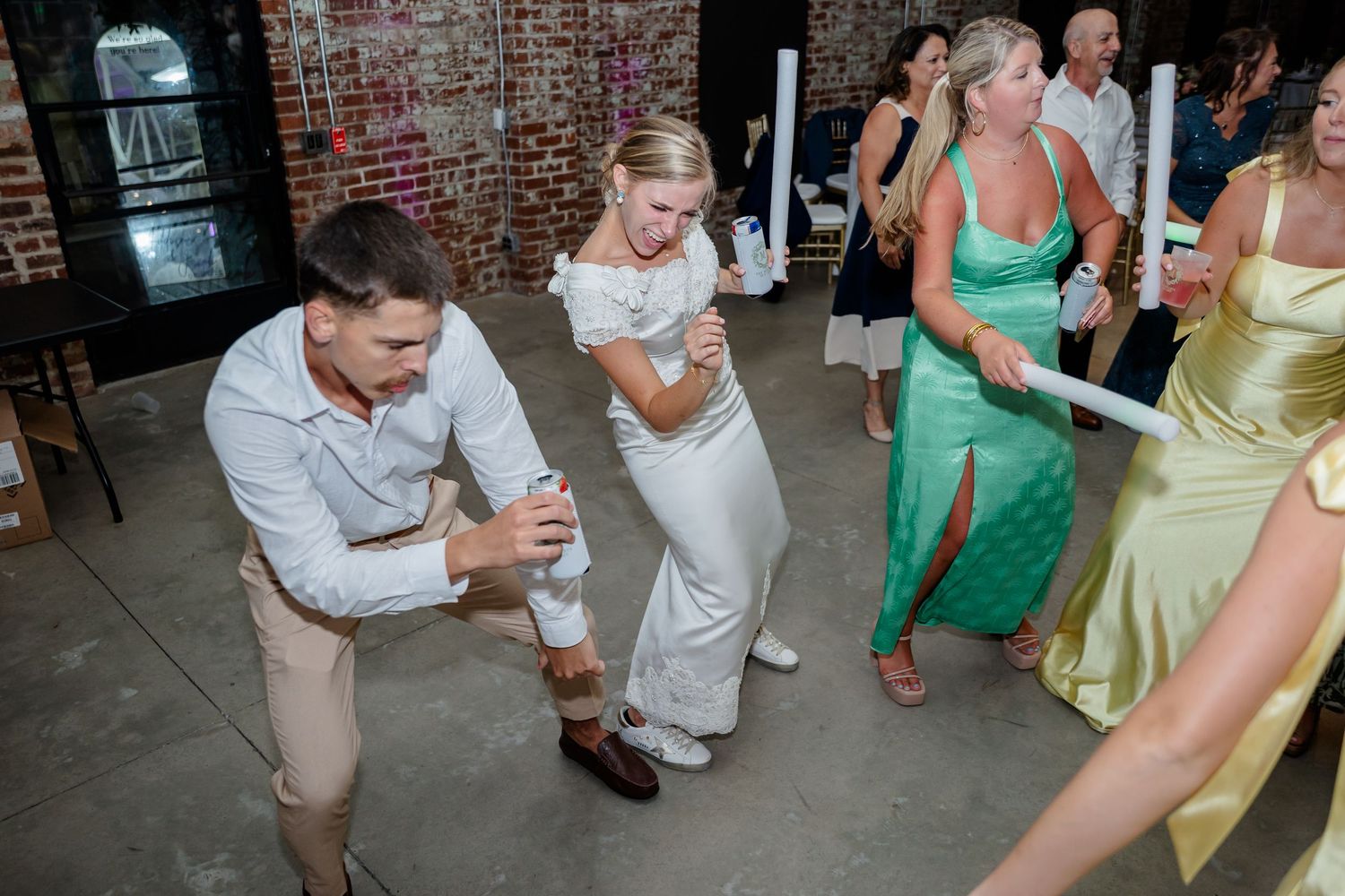 Lively dance floor scene at a wedding reception with guests in bright summer colors.