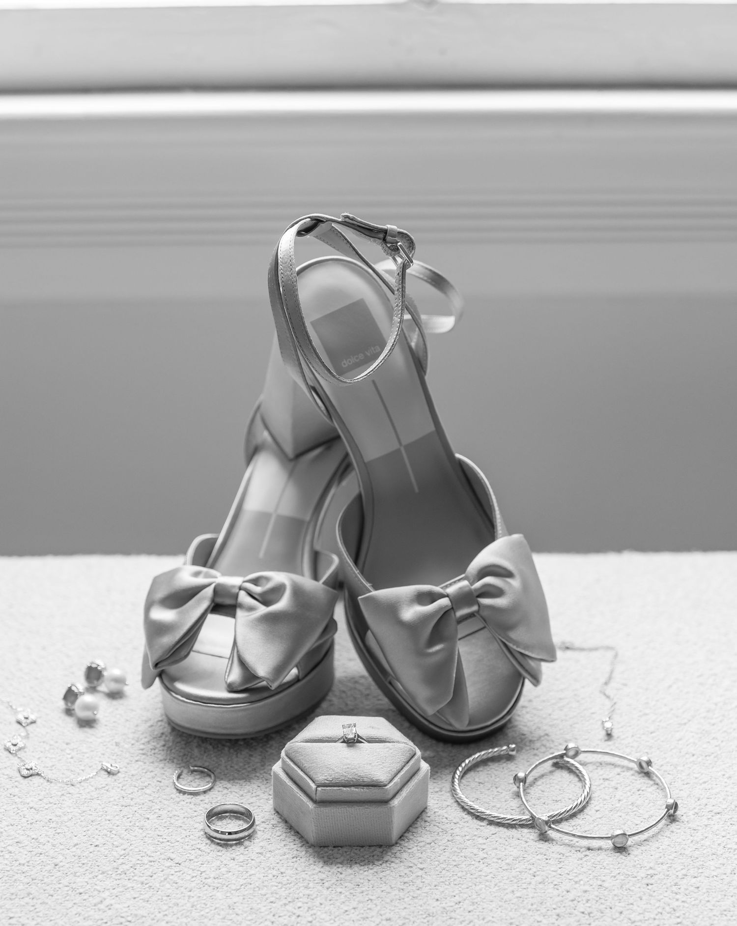 Silver wedding rings and elegant bridal shoes arranged in a minimalist composition on a light background.