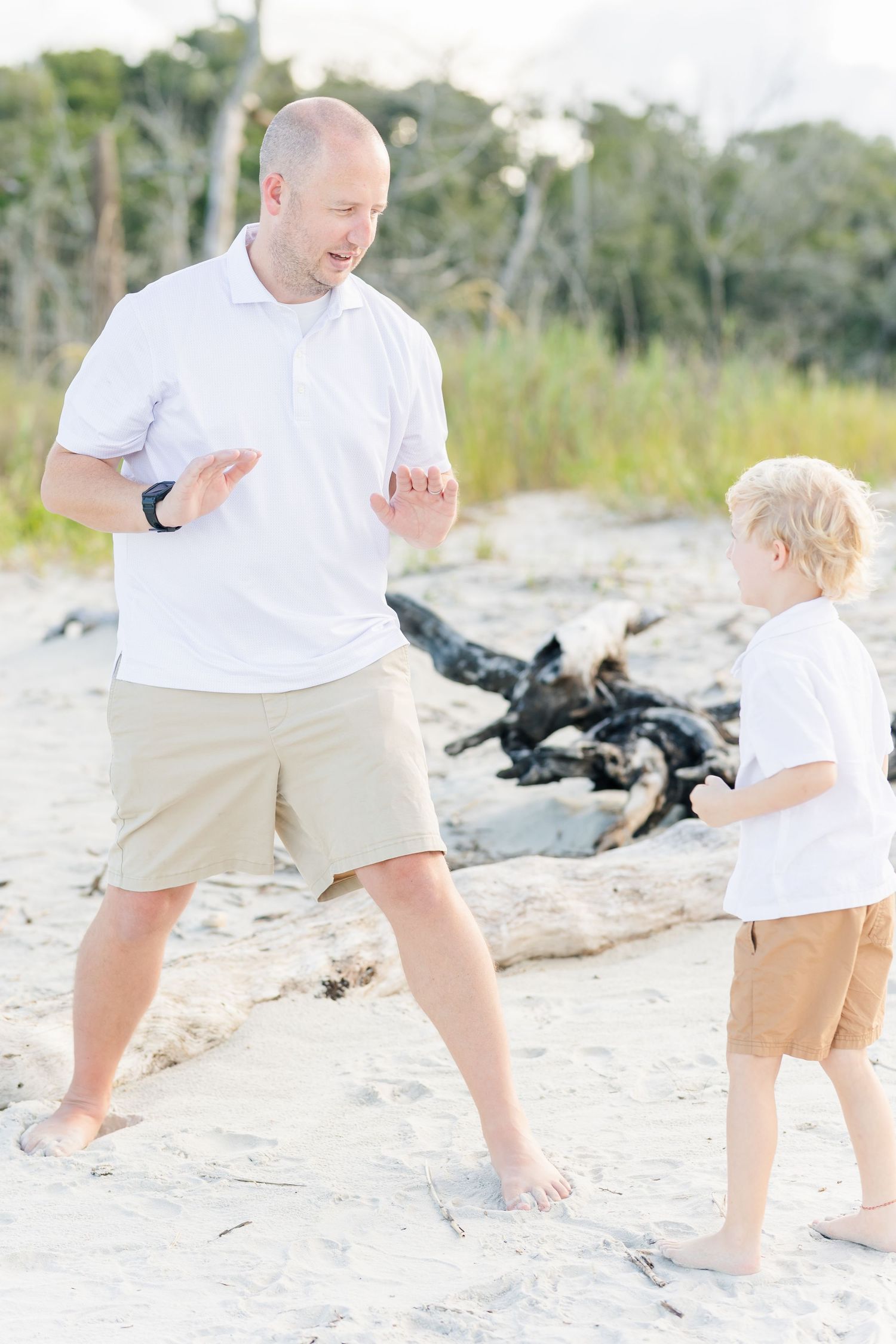 A playful moment on the beach with driftwood in the background.
