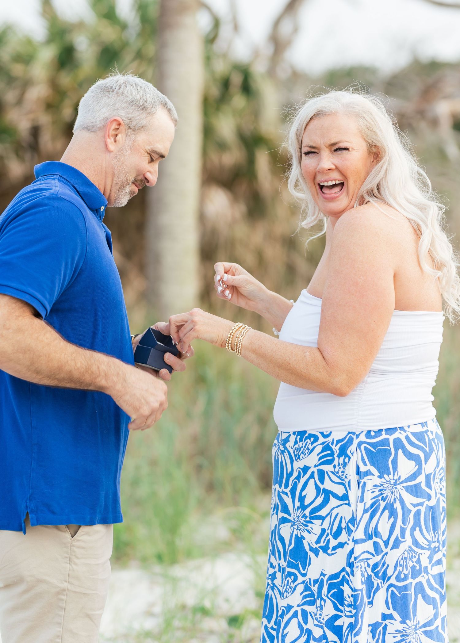 A couple shares a joyful moment while outdoors, with blue and white coordinated outfits against a natural backdrop.