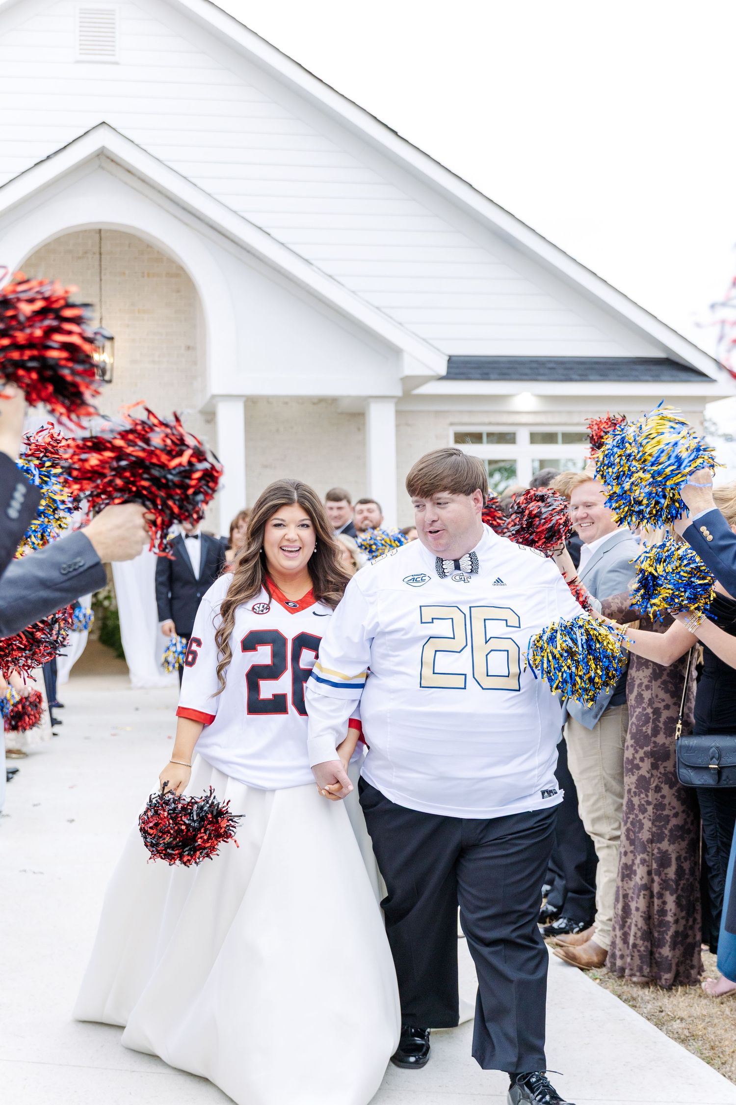 Newlyweds exit chapel wearing matching football jerseys number 26 as guests cheer with colorful pom-poms.