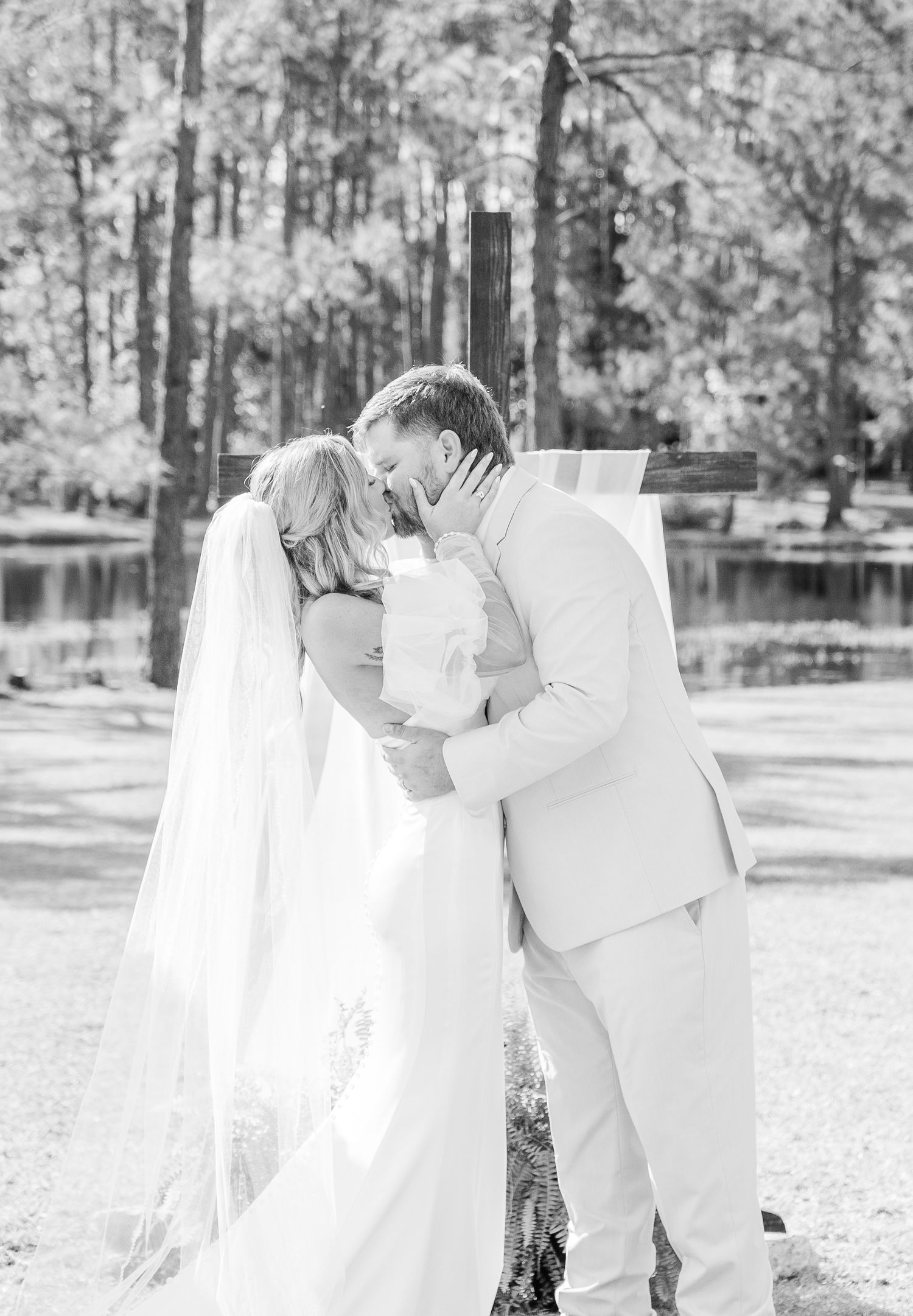 Romantic black and white portrait of couple embracing during outdoor wedding ceremony.