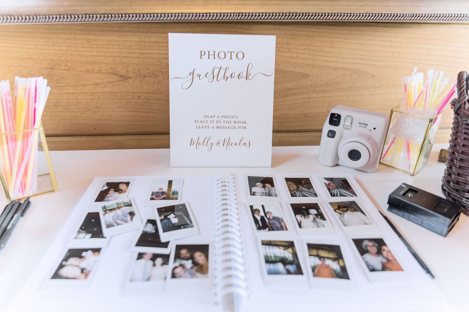 Photo album display with Instax camera and decorative straws arranged on wooden table.
