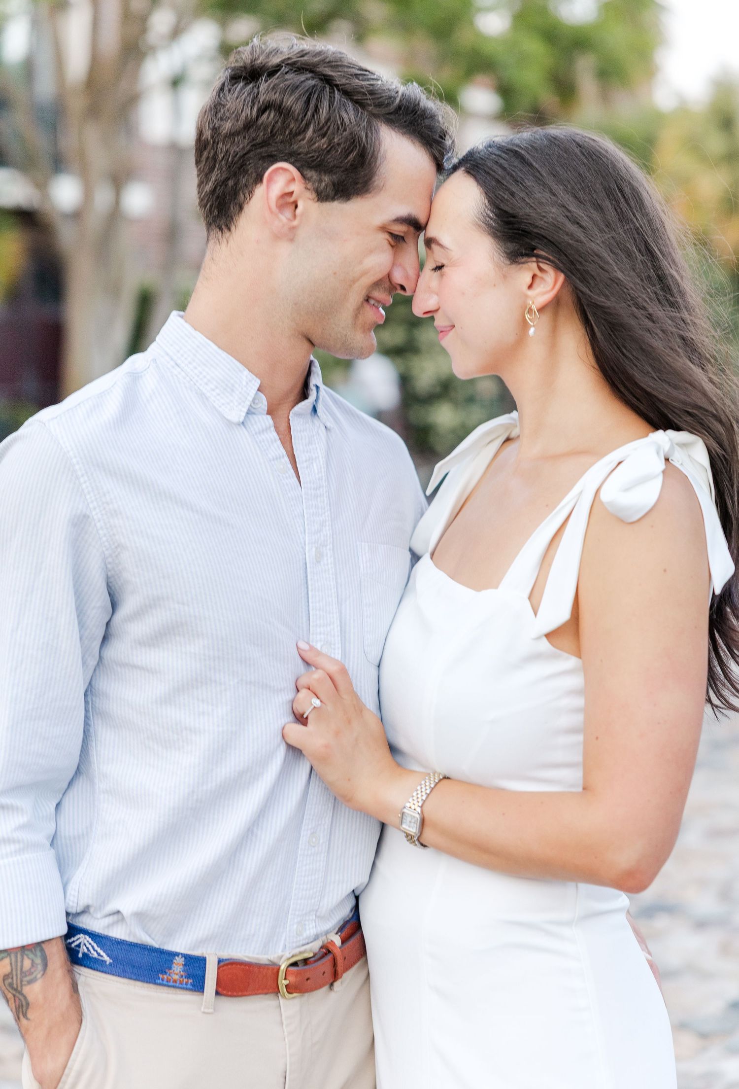 Couple leaning in close and smiling at each other during outdoor engagement portrait session.