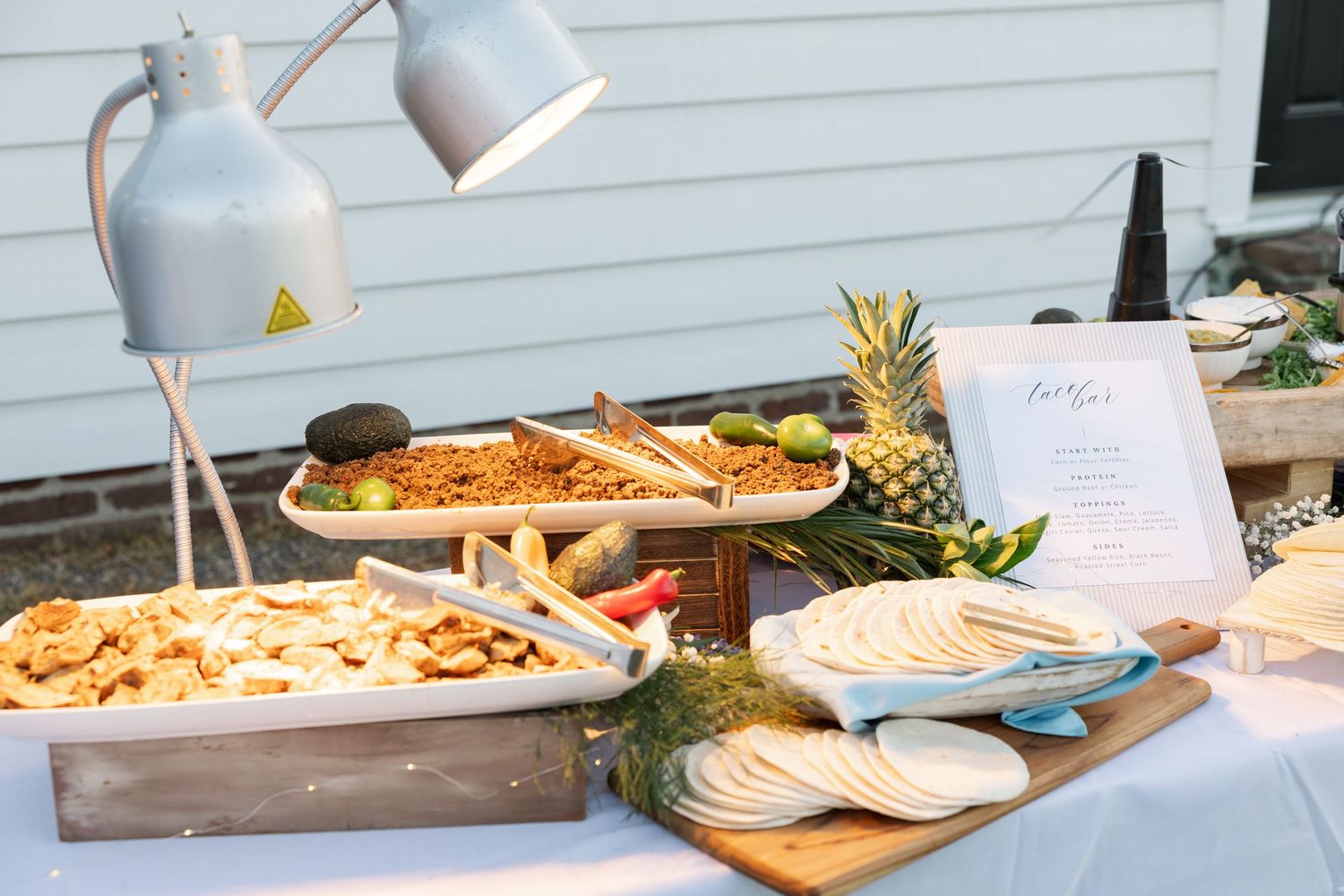 Outdoor wedding reception food table with appetizers, pineapple, and tortillas.