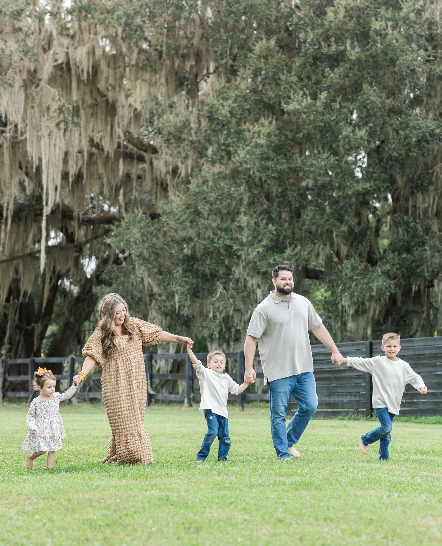 A playful sequence of people lying in the grass under Spanish moss trees creating a domino-like falling effect.