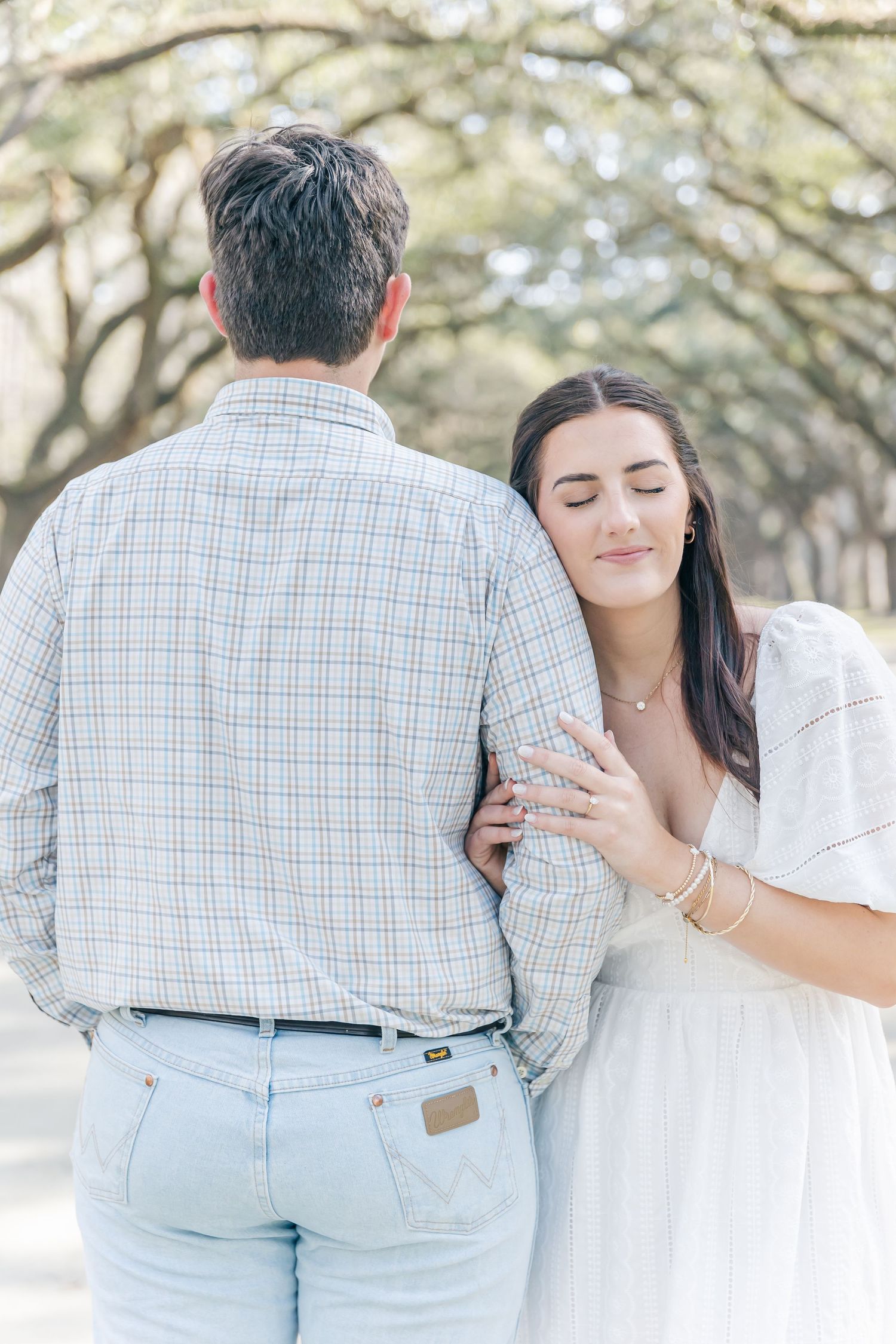 A tender moment captured between a couple beneath an oak tree canopy.