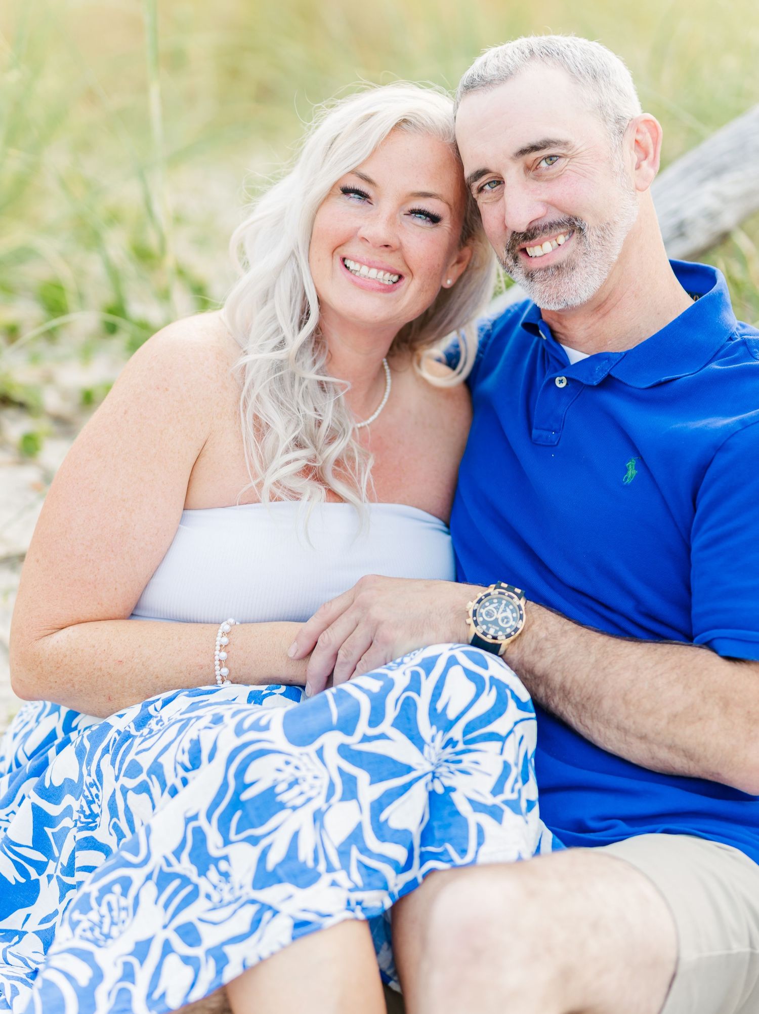 A couple sits together outdoors wearing coordinated blue and white outfits on a sunny day.