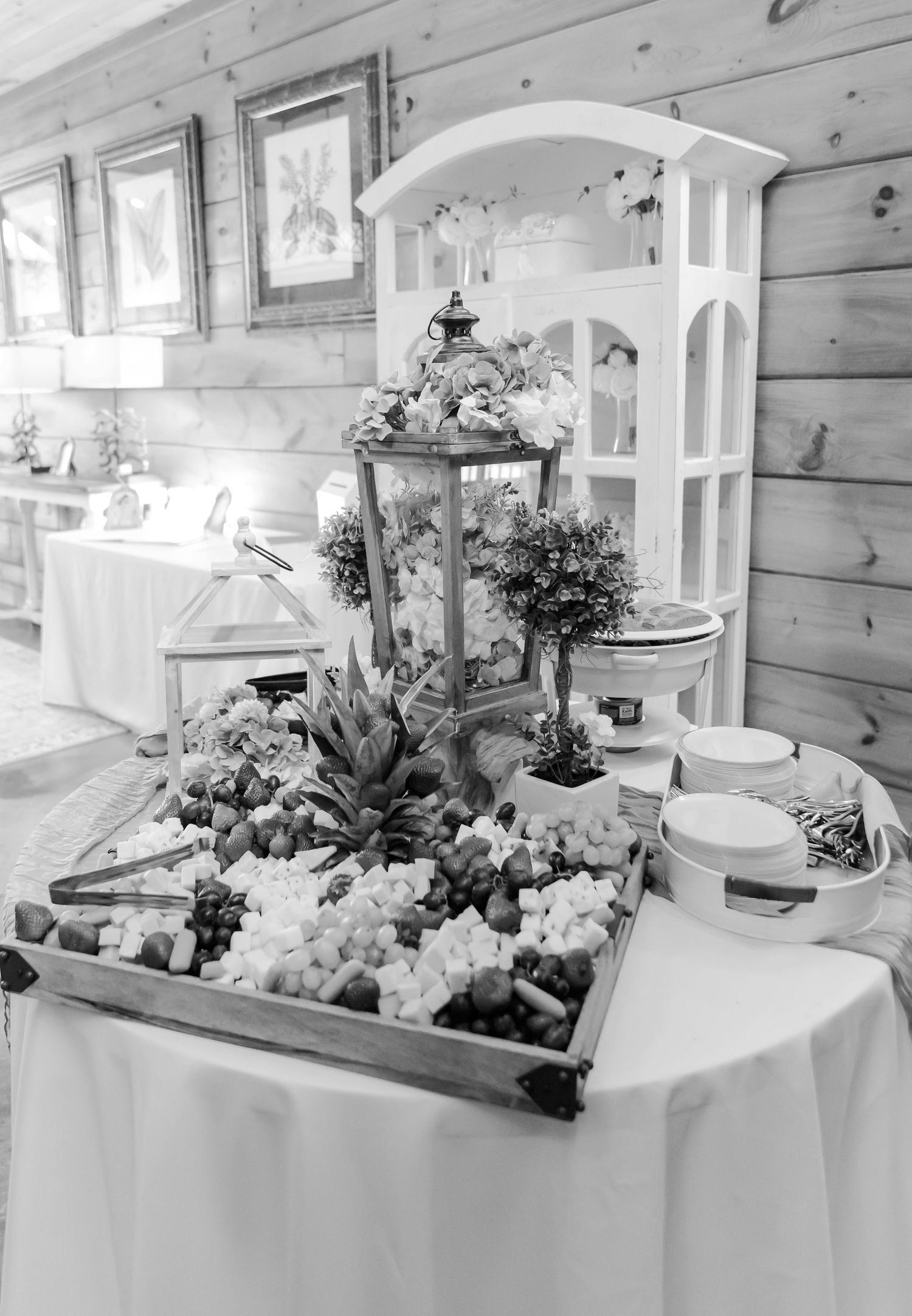 Elegant wedding reception decor featuring a white lantern centerpiece with floral arrangements and greenery on a linen-covered table.