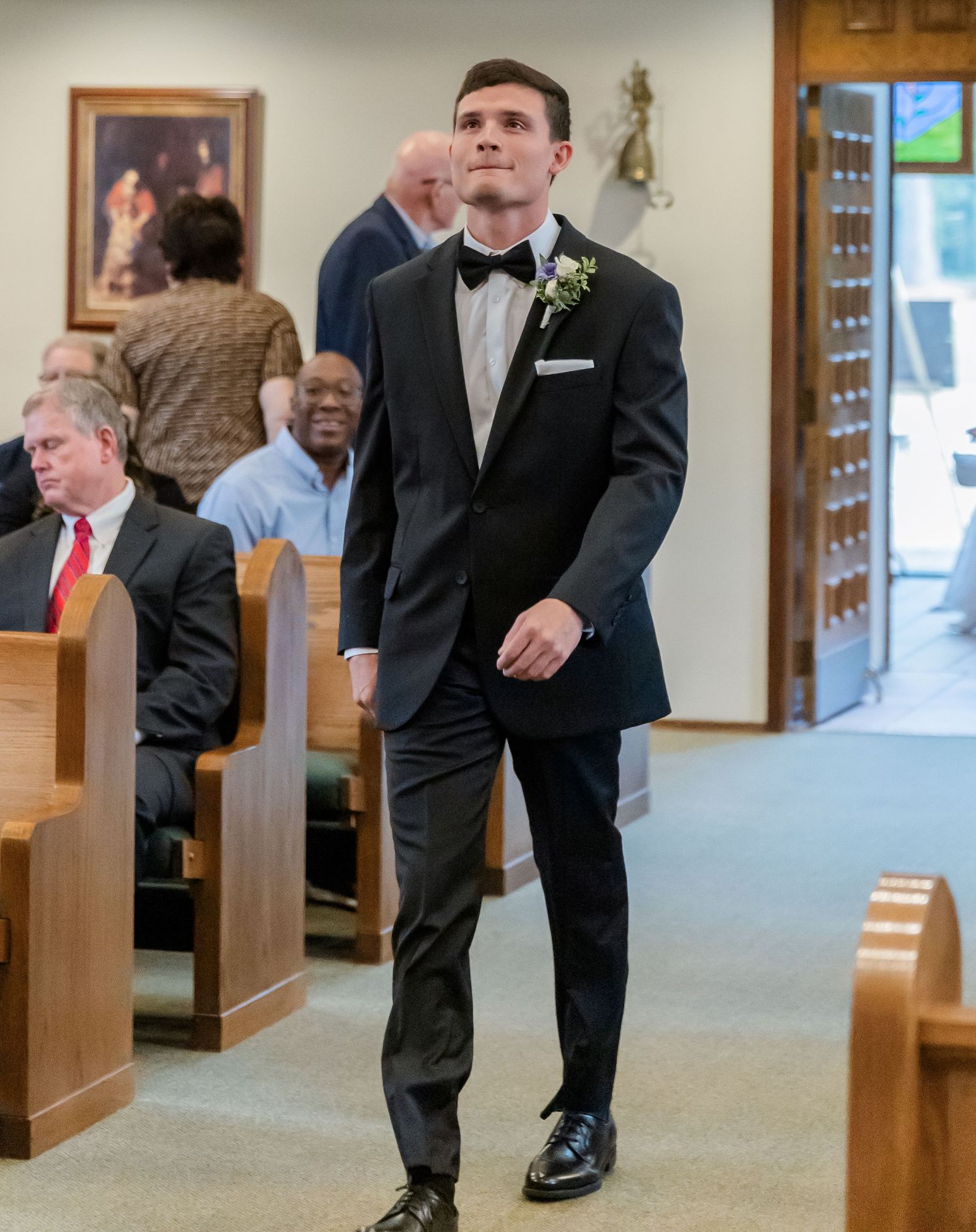Church aisle with wooden pews and carpeted floor during ceremony.
