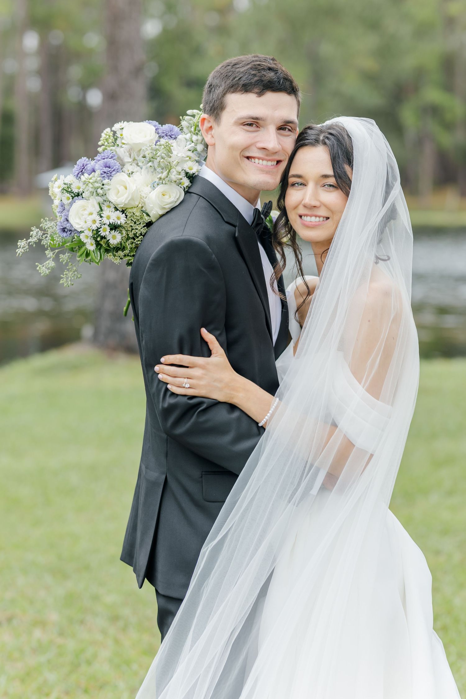 A bride and groom share joyful moments during their outdoor wedding photoshoot in a natural setting.