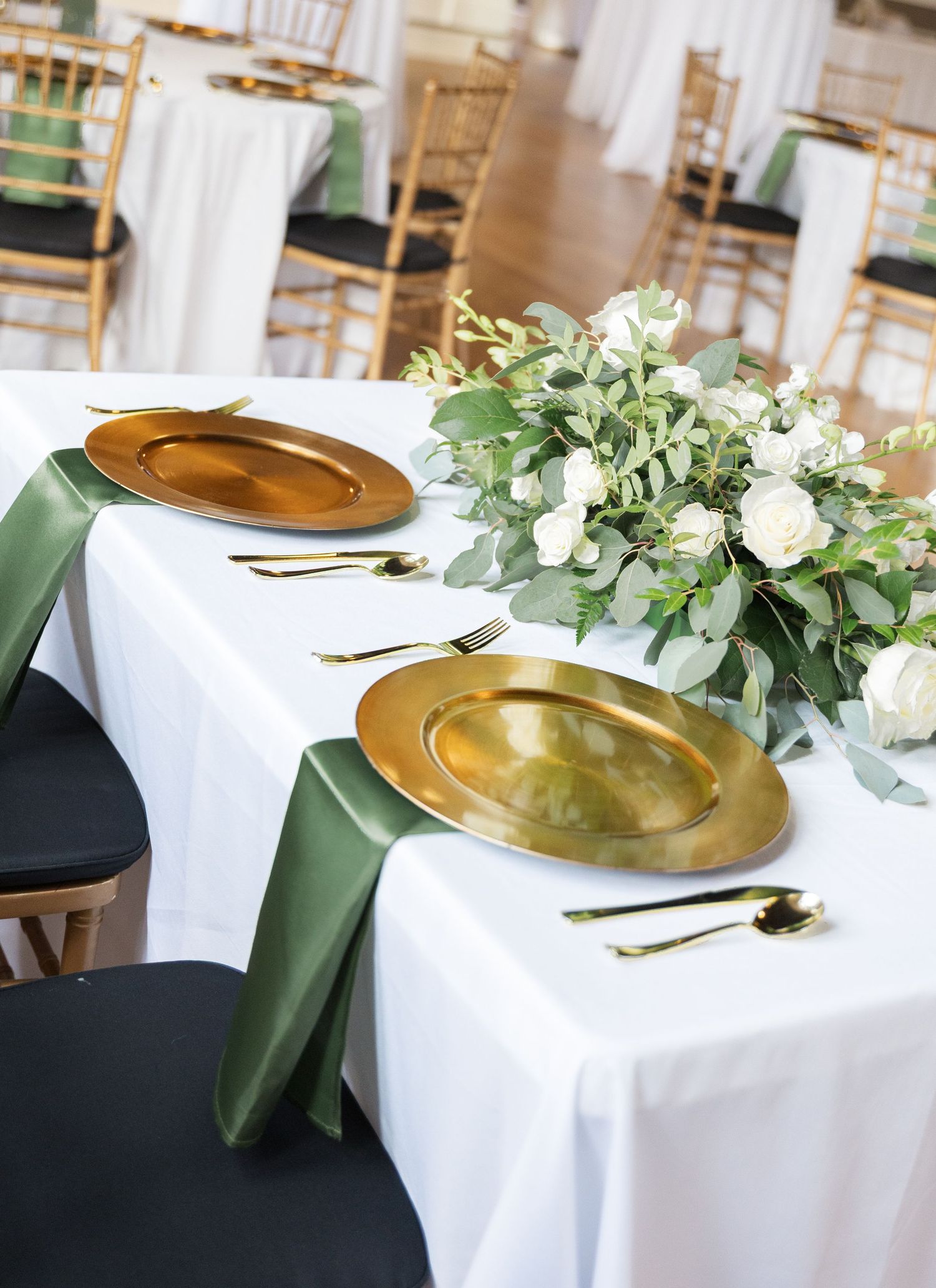 Elegant table settings with gold charger plates and white floral centerpieces create a sophisticated dining atmosphere.