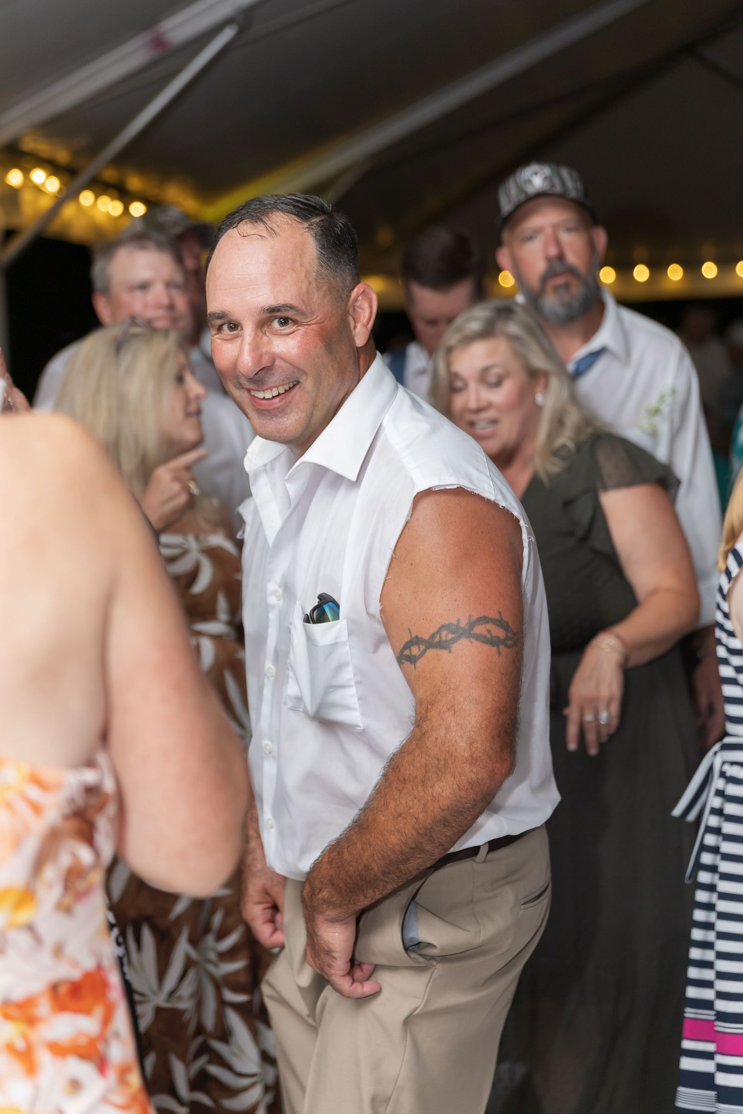 Party guests in casual attire dancing and socializing at outdoor evening event.