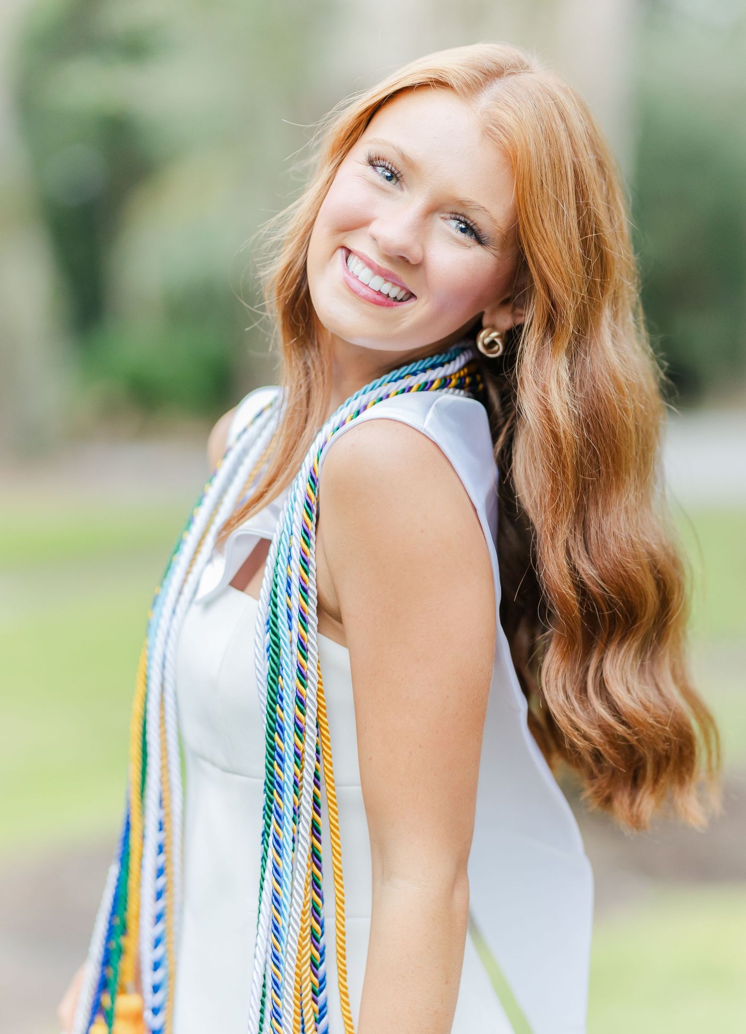 Natural lighting brings out vibrant details in fashion portrait against soft green outdoor backdrop.