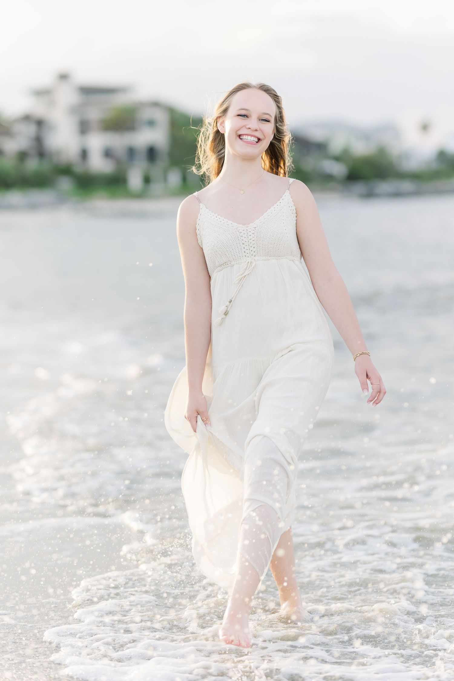 Carefree beachside photo shoot with waves and white dress creating movement.