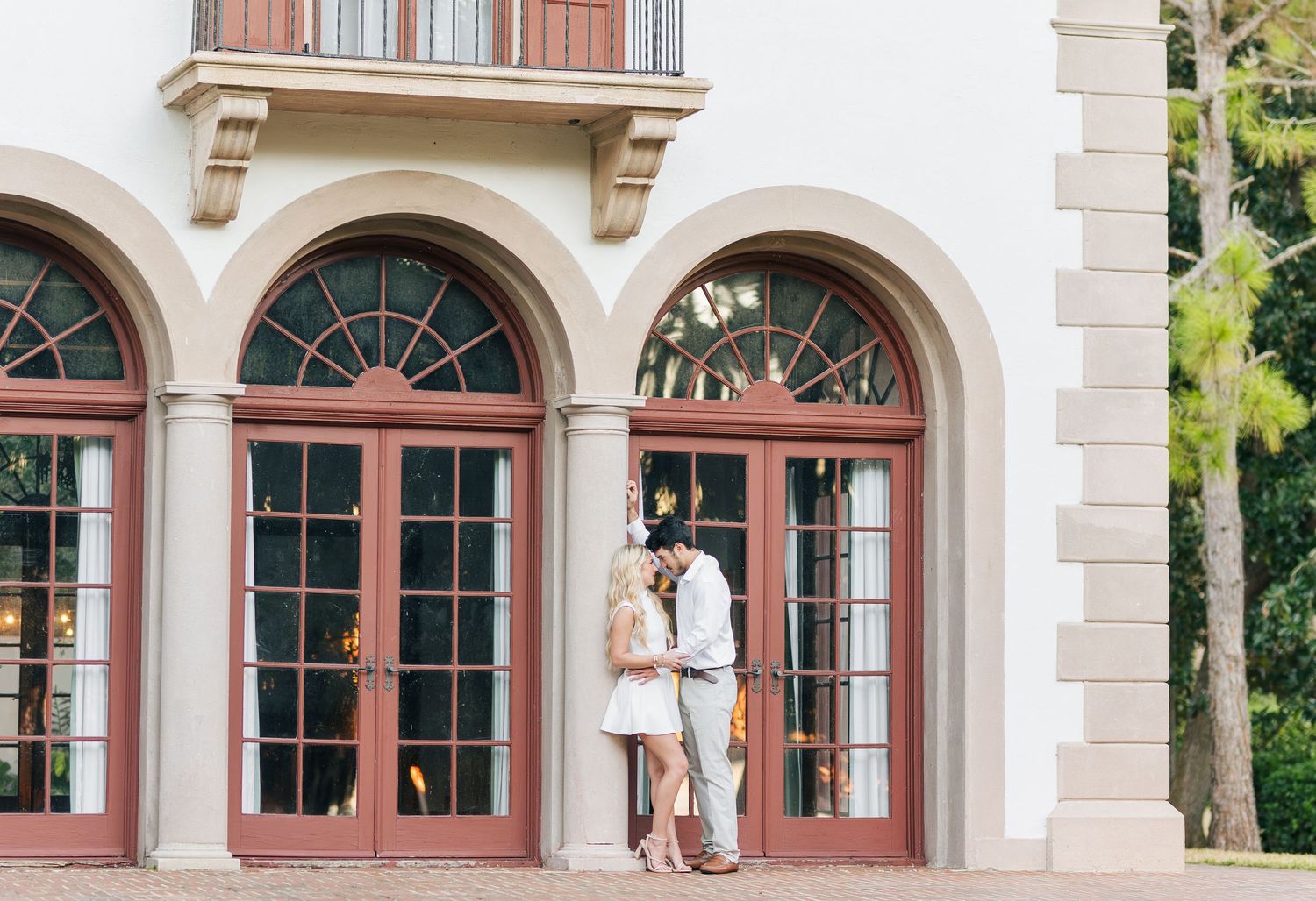 Architectural detail of arched windows with red trim and white stone facade on a historic building exterior.