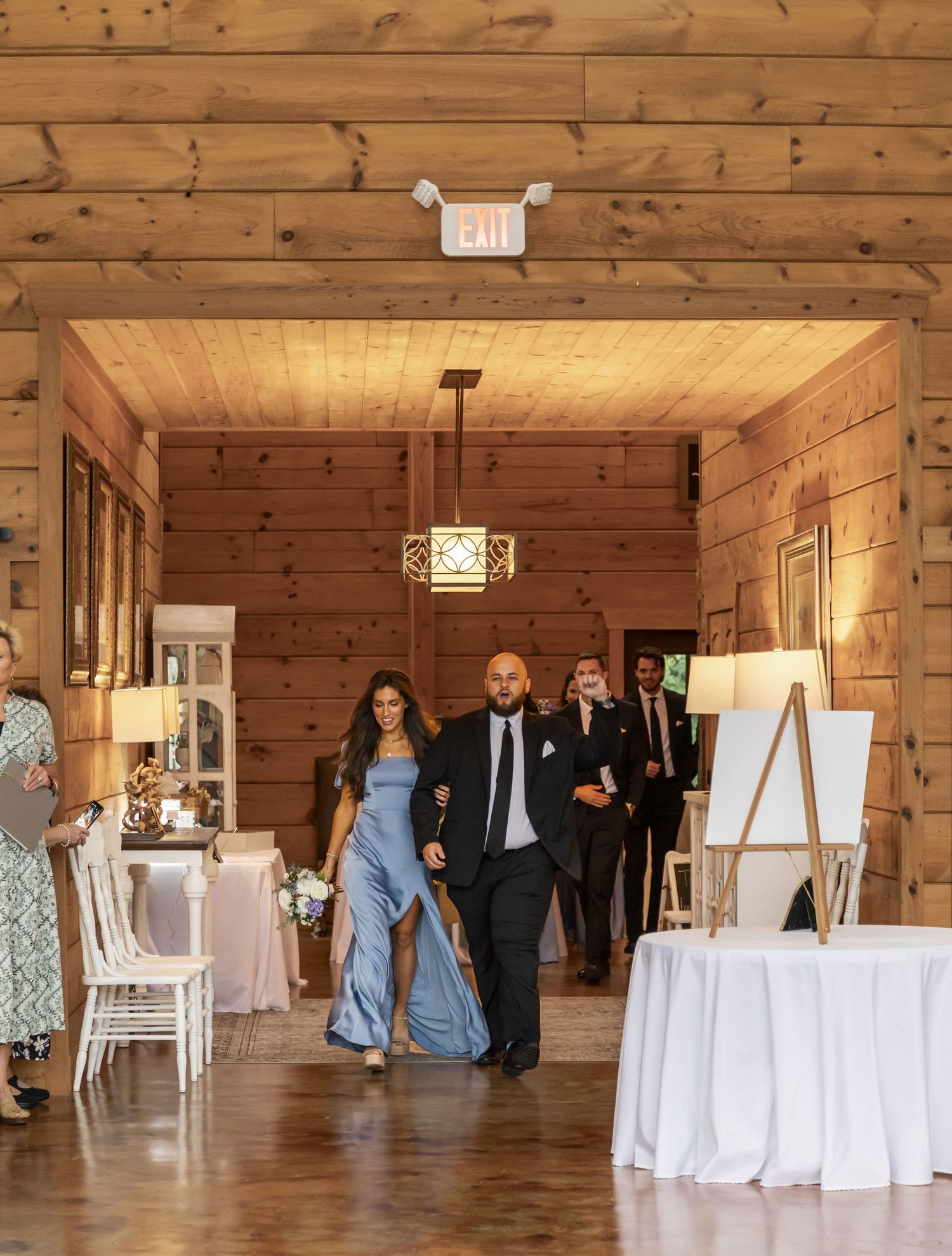 Rustic wooden barn venue interior decorated with white linens and chairs for an elegant wedding reception.